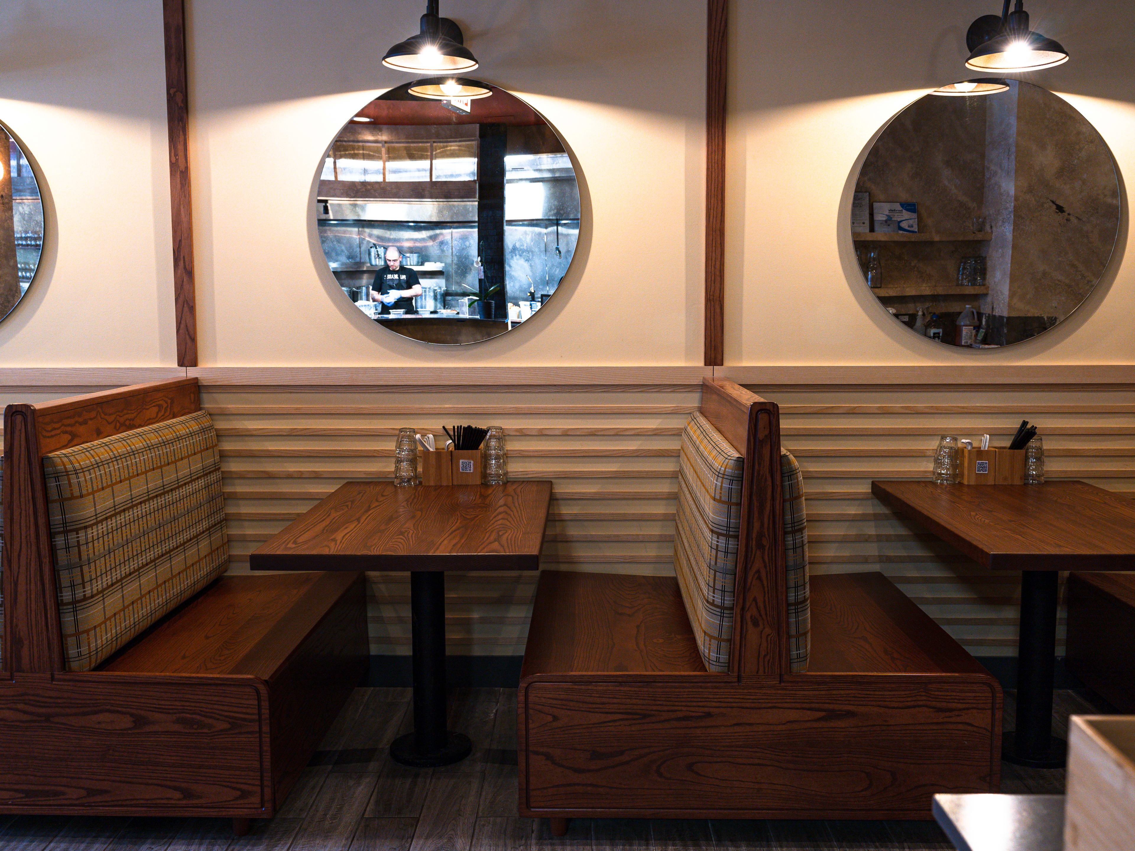 Wooden booths and mirrors and lamps hanging on the walls.