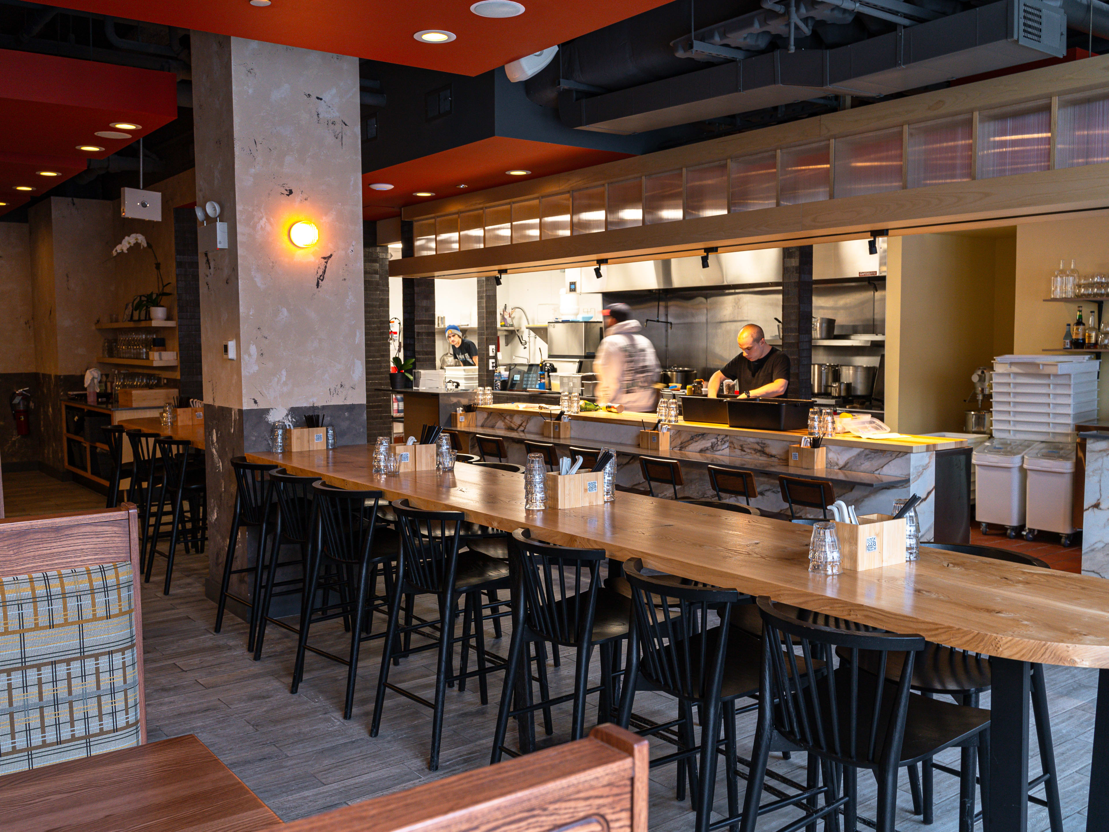 A dining room with a long communal table and open kitchen.