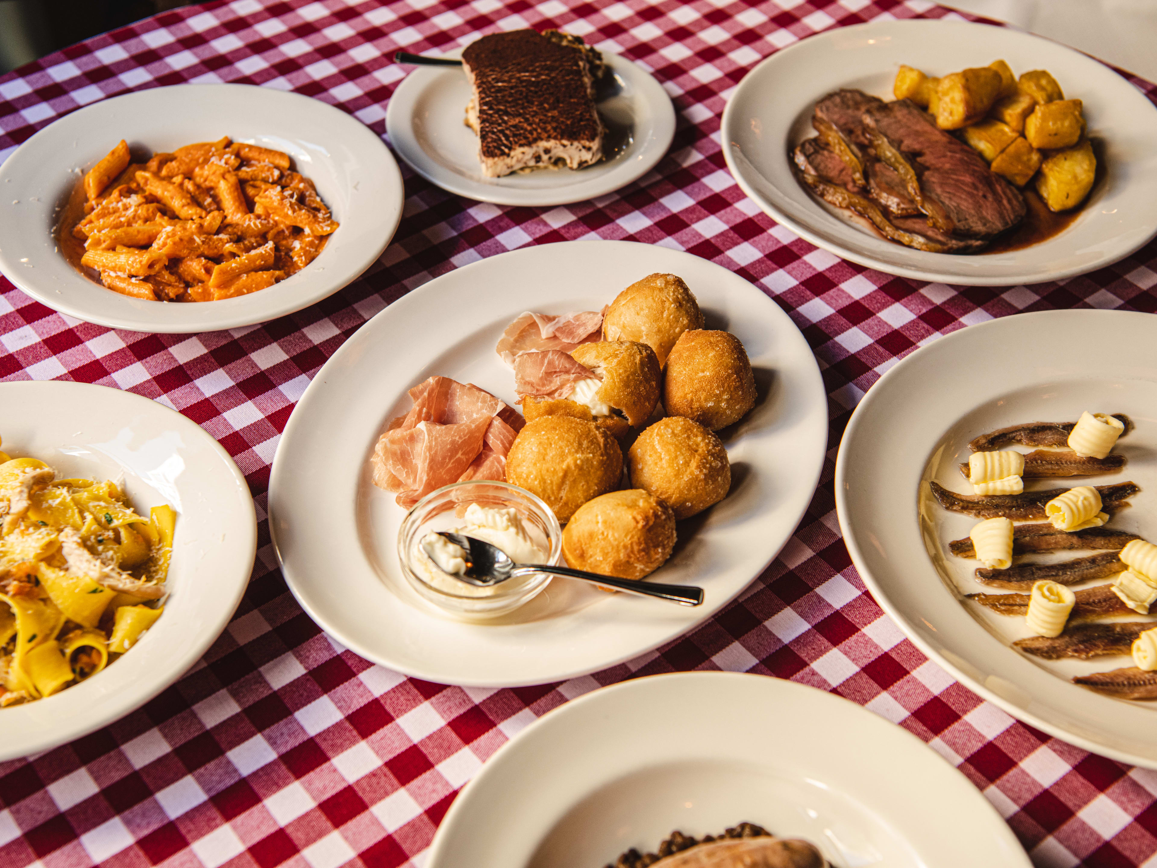 A spread of dishes on a gingham table at Trattoria Brutto.