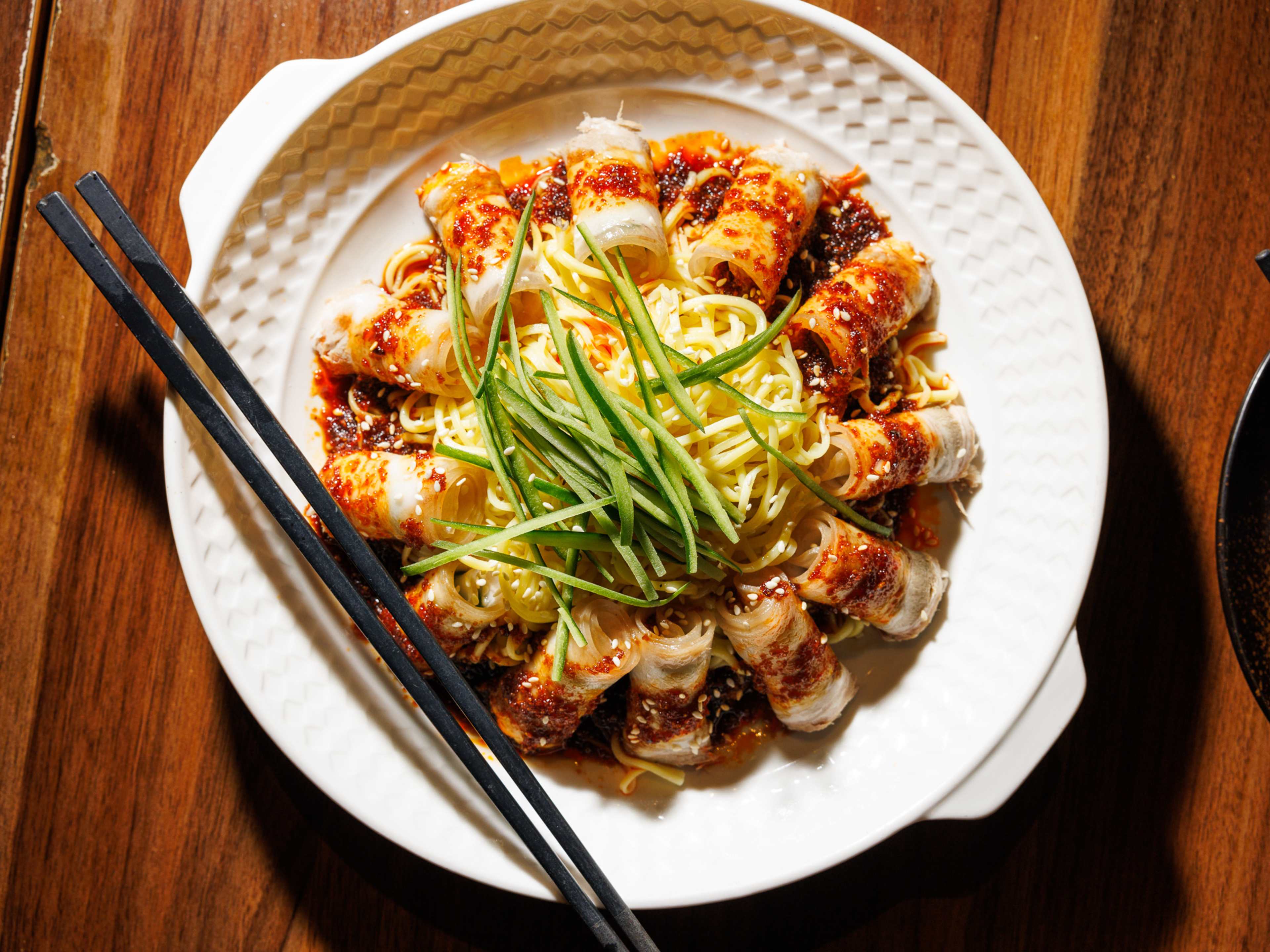 Rolled pork belly and noodles on a white plate.