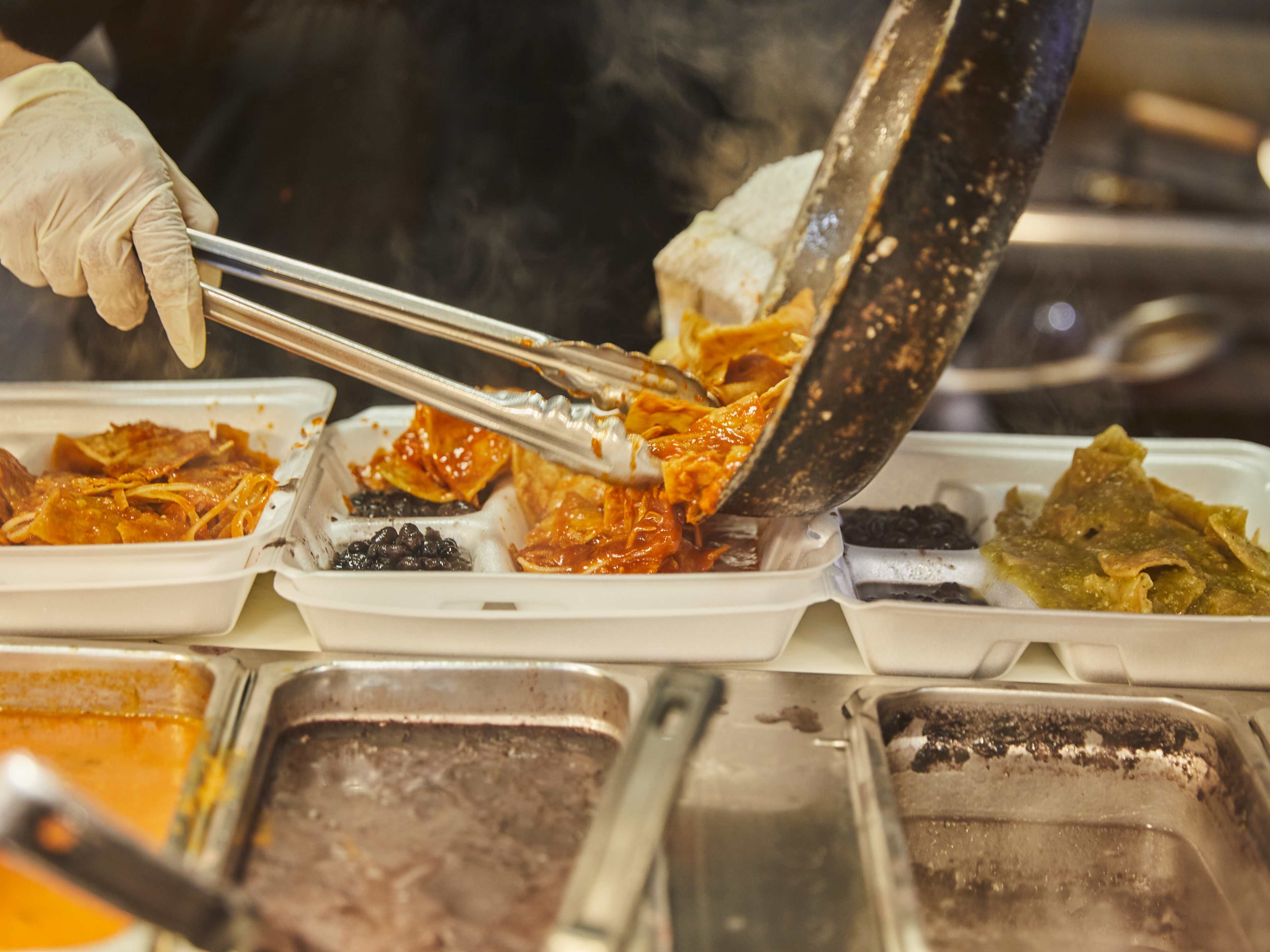 Pouring meat into to go containers at La Mayordomía.