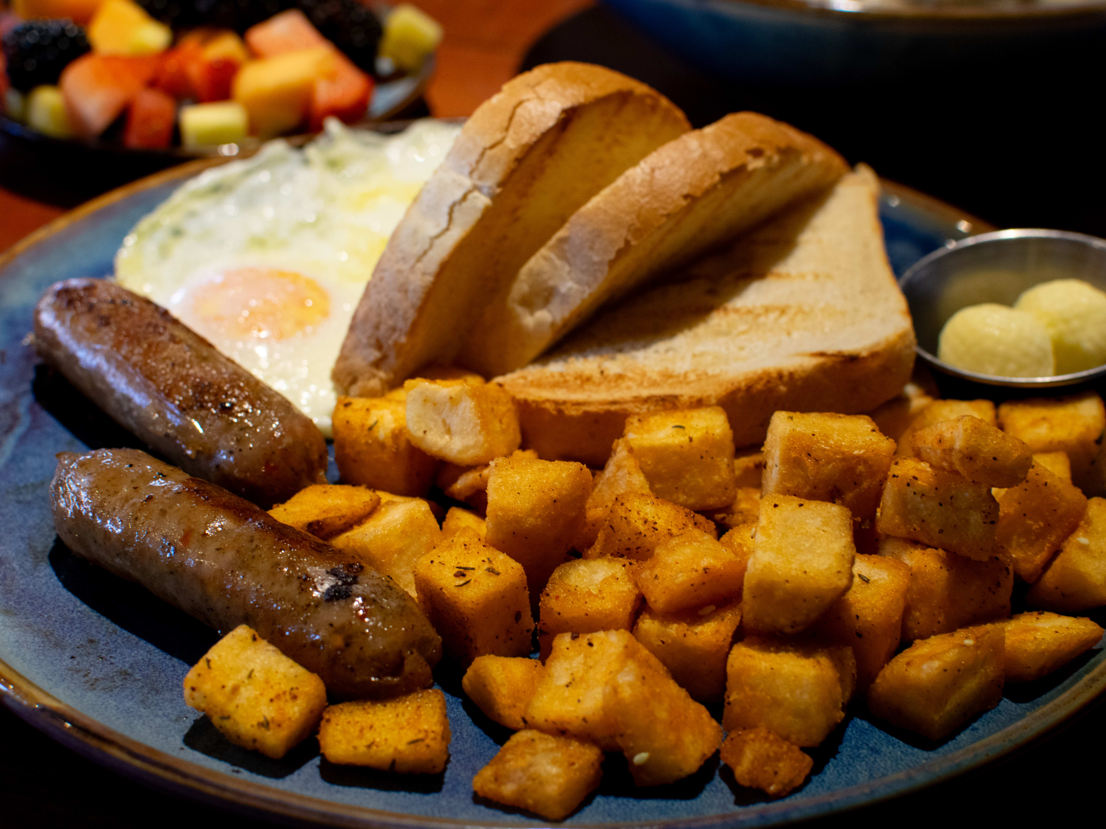 A plate of home potatoes, eggs, sausages, and toast.