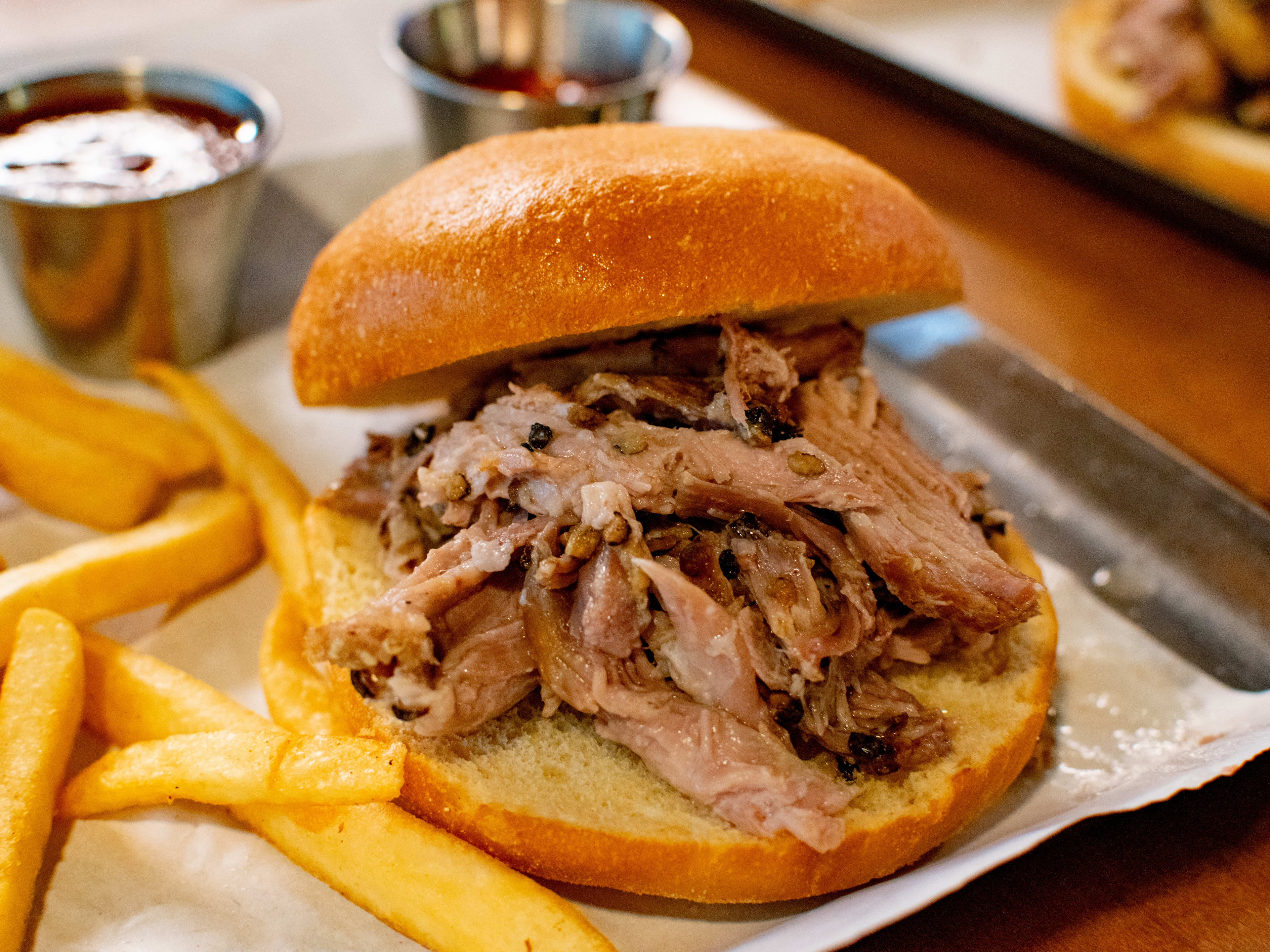 A barbecue sandwich and some fries on a tray.