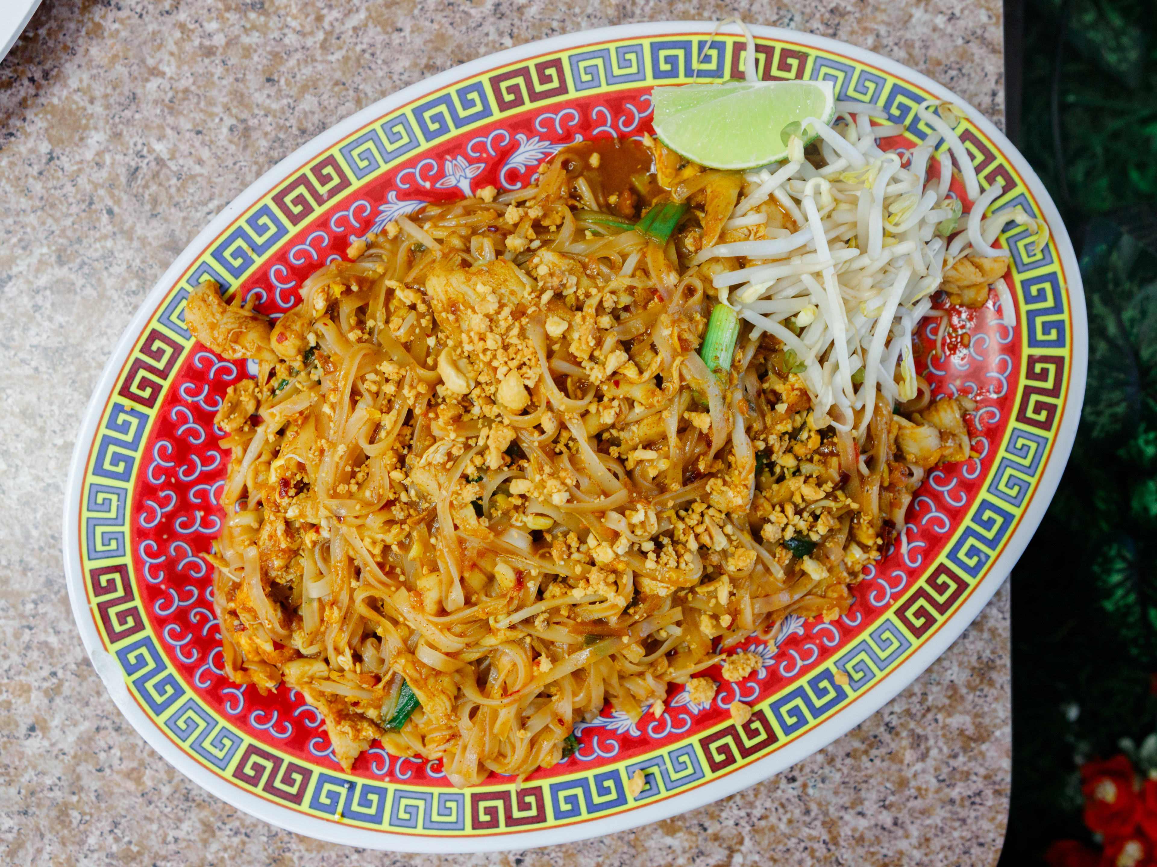 colorful plate of pad thai noodles with lime and bean sprouts