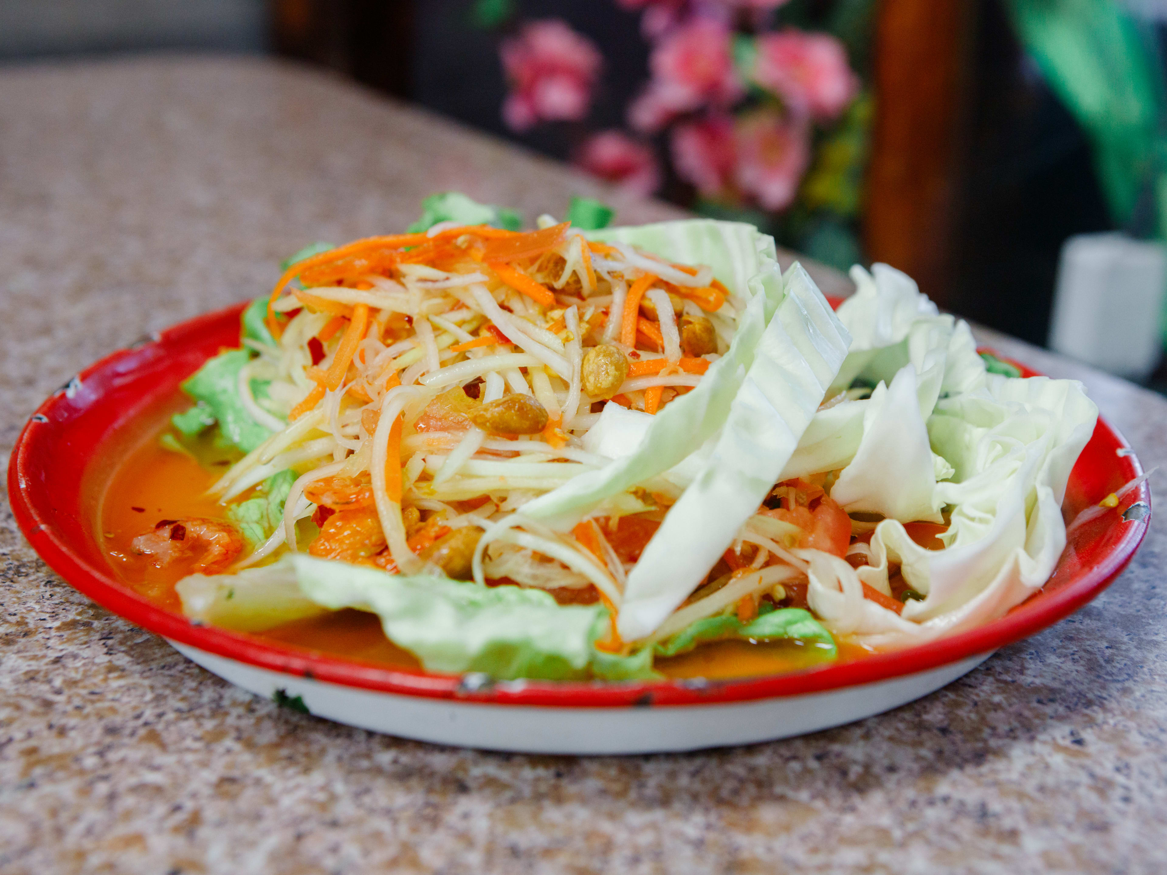 thai shaved papaya salad on a red plate