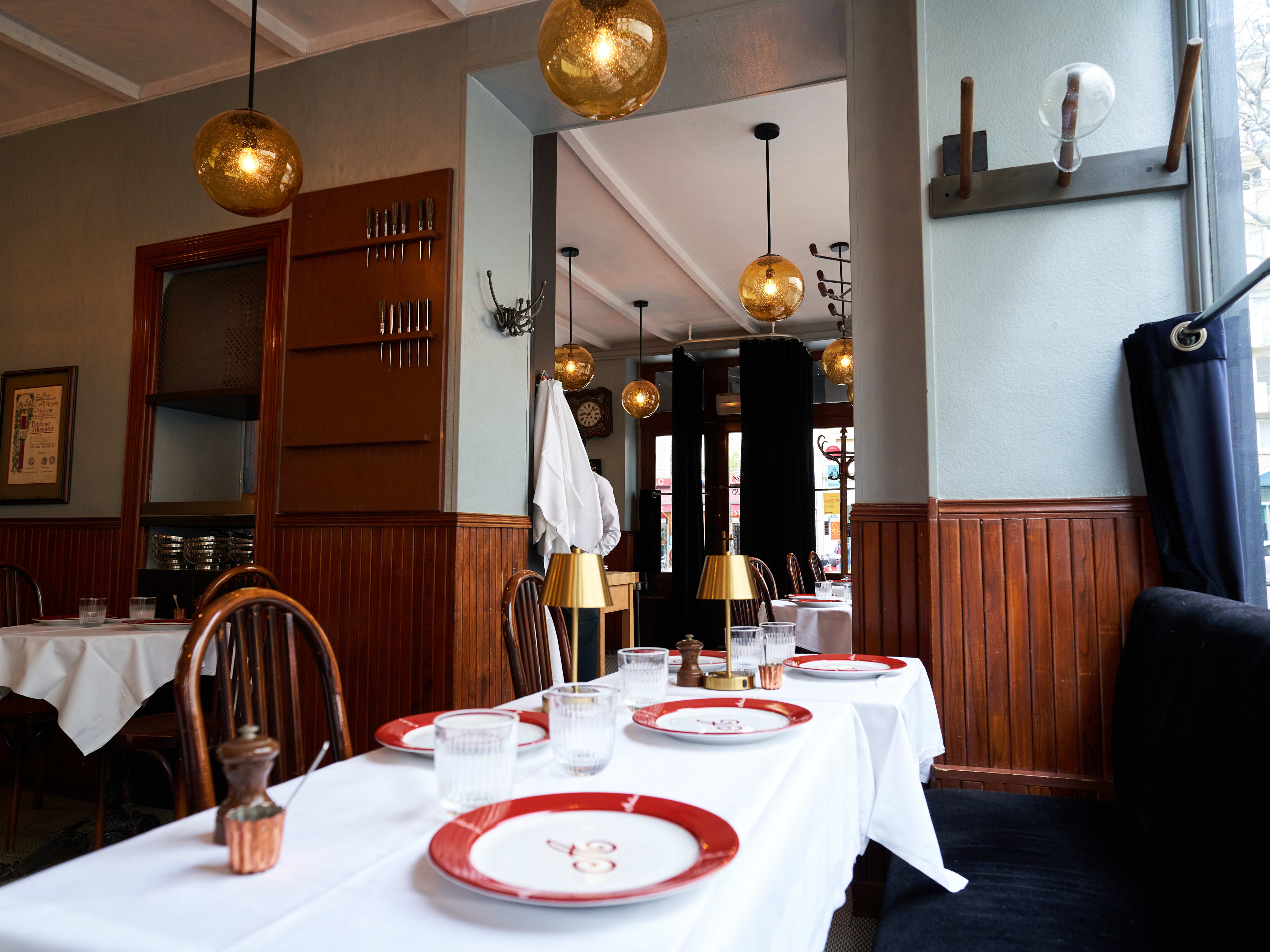 Interior dining room with long set table at gold lamps at Restaurant Astier