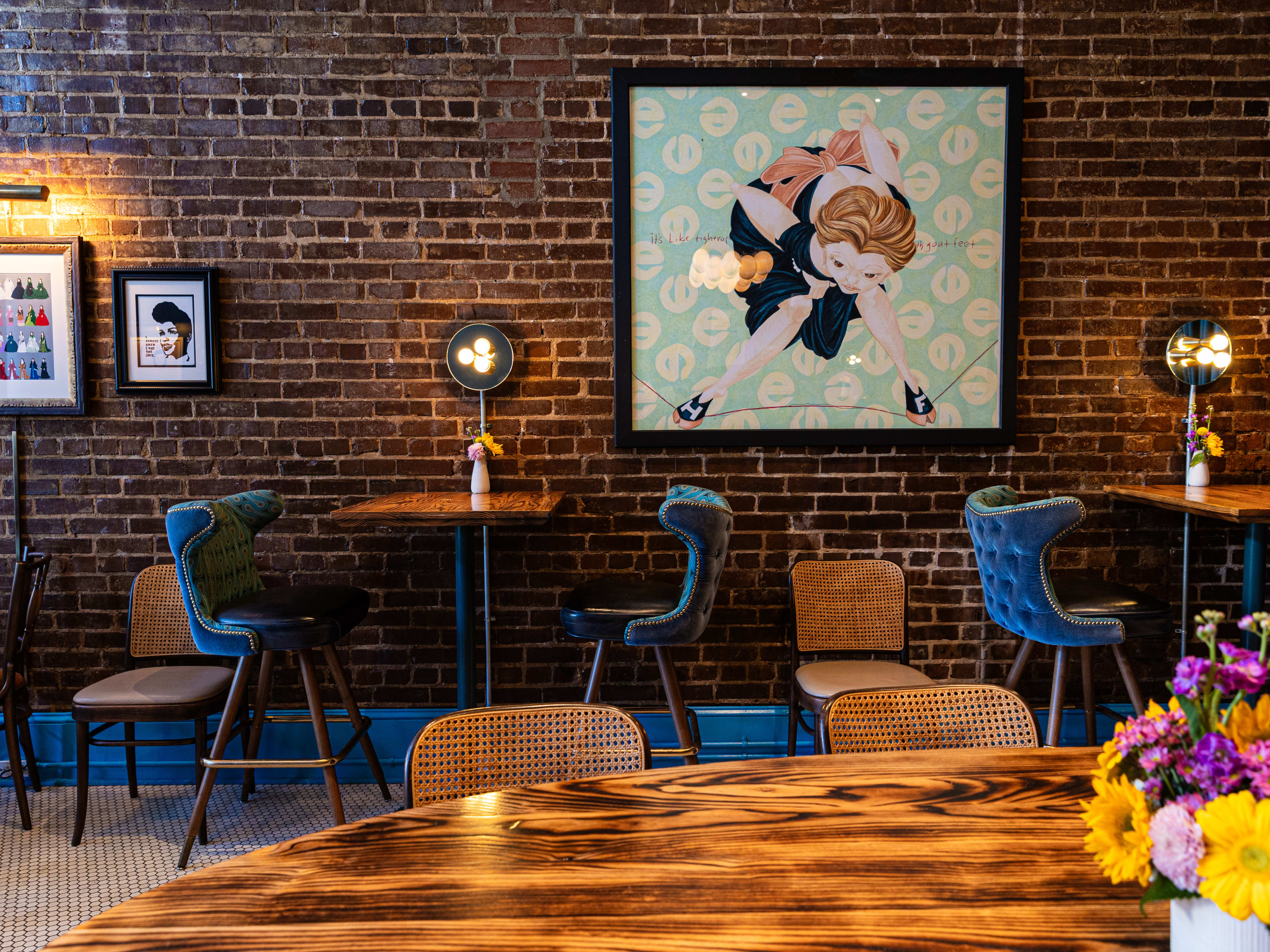 dining room with blue chairs, brick wall, framed photos and flowers