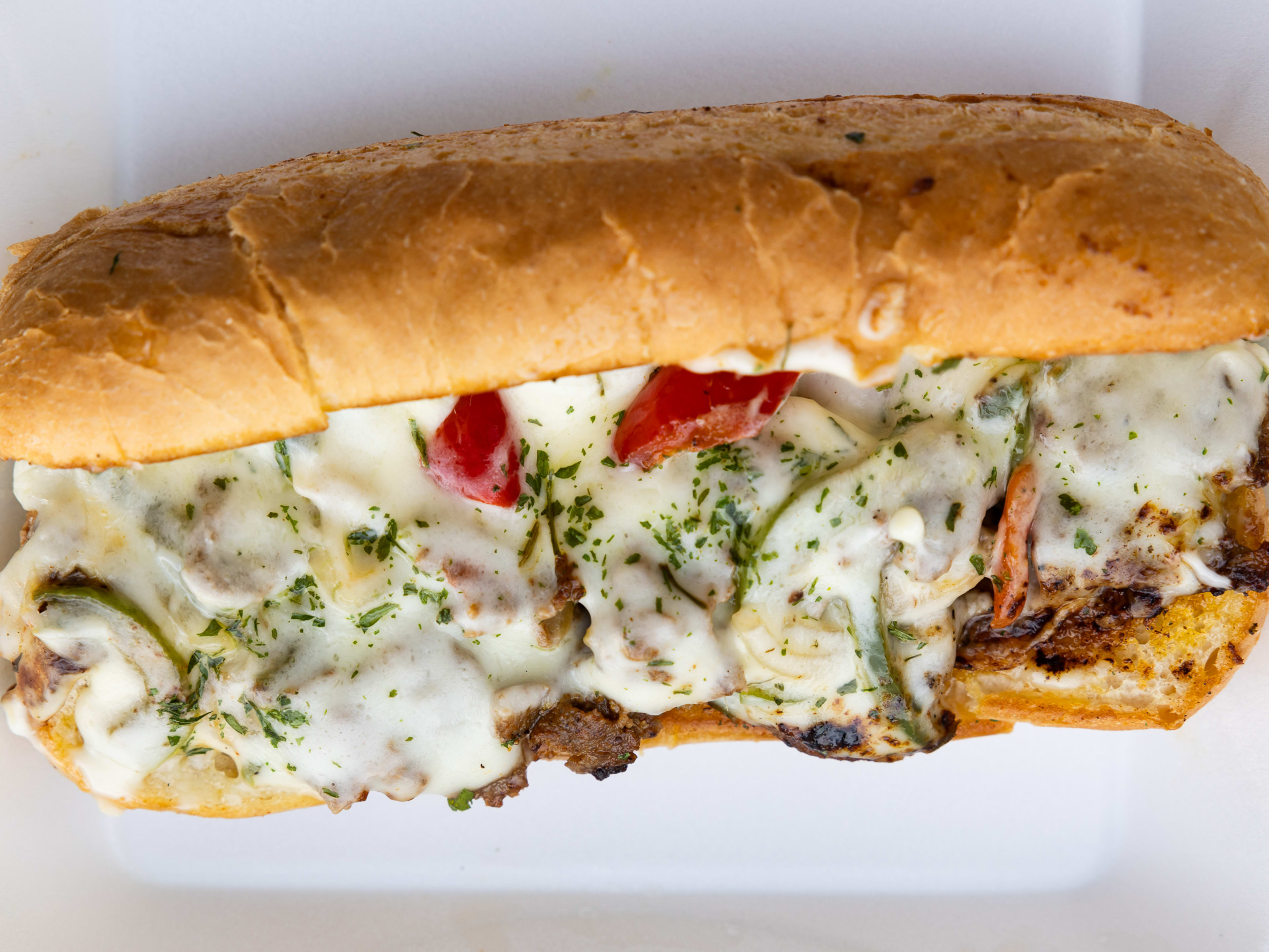 A cheesesteak with red peppers.