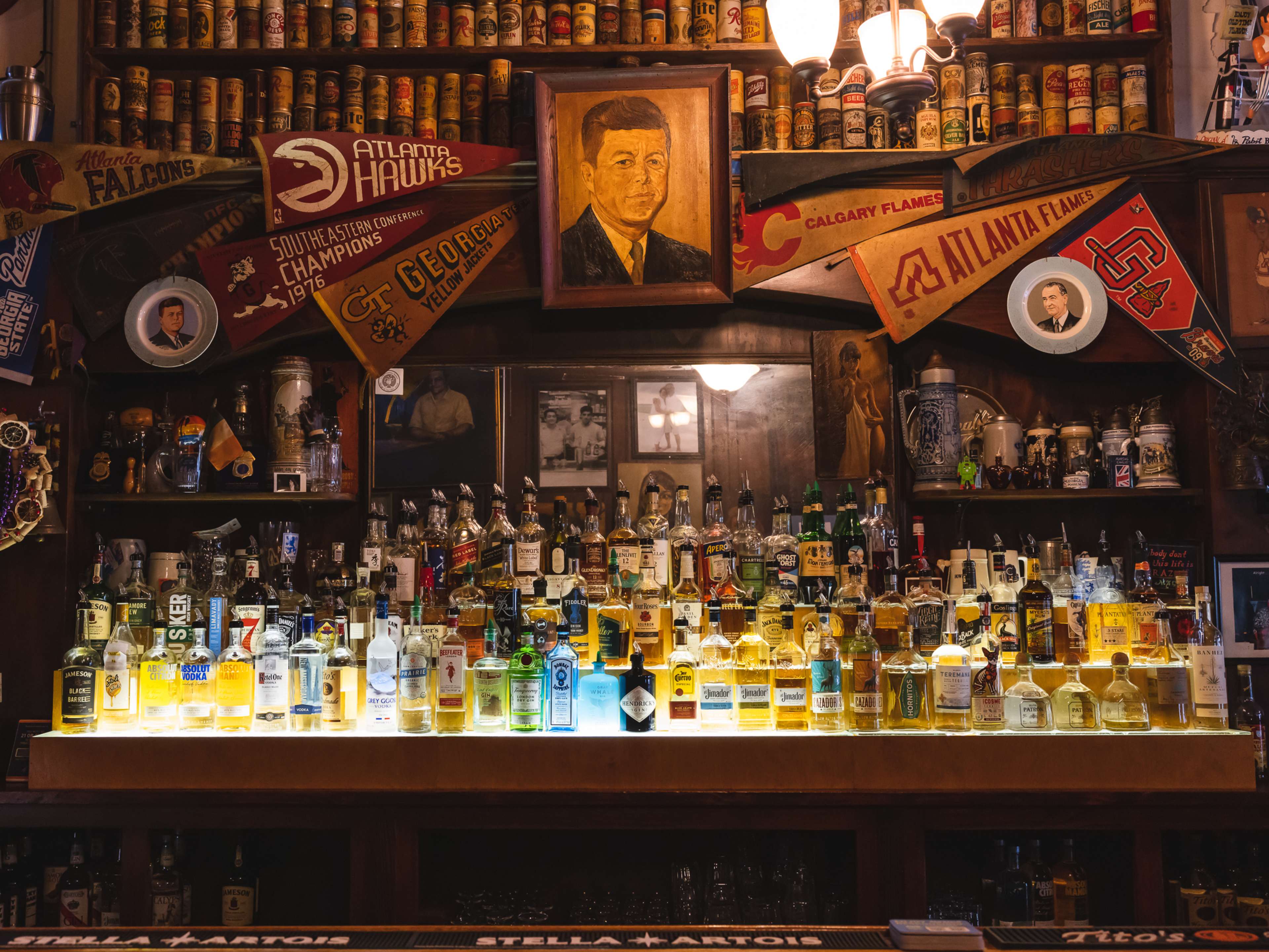 A bar with sports pennants and a painting of John F. Kennedy.