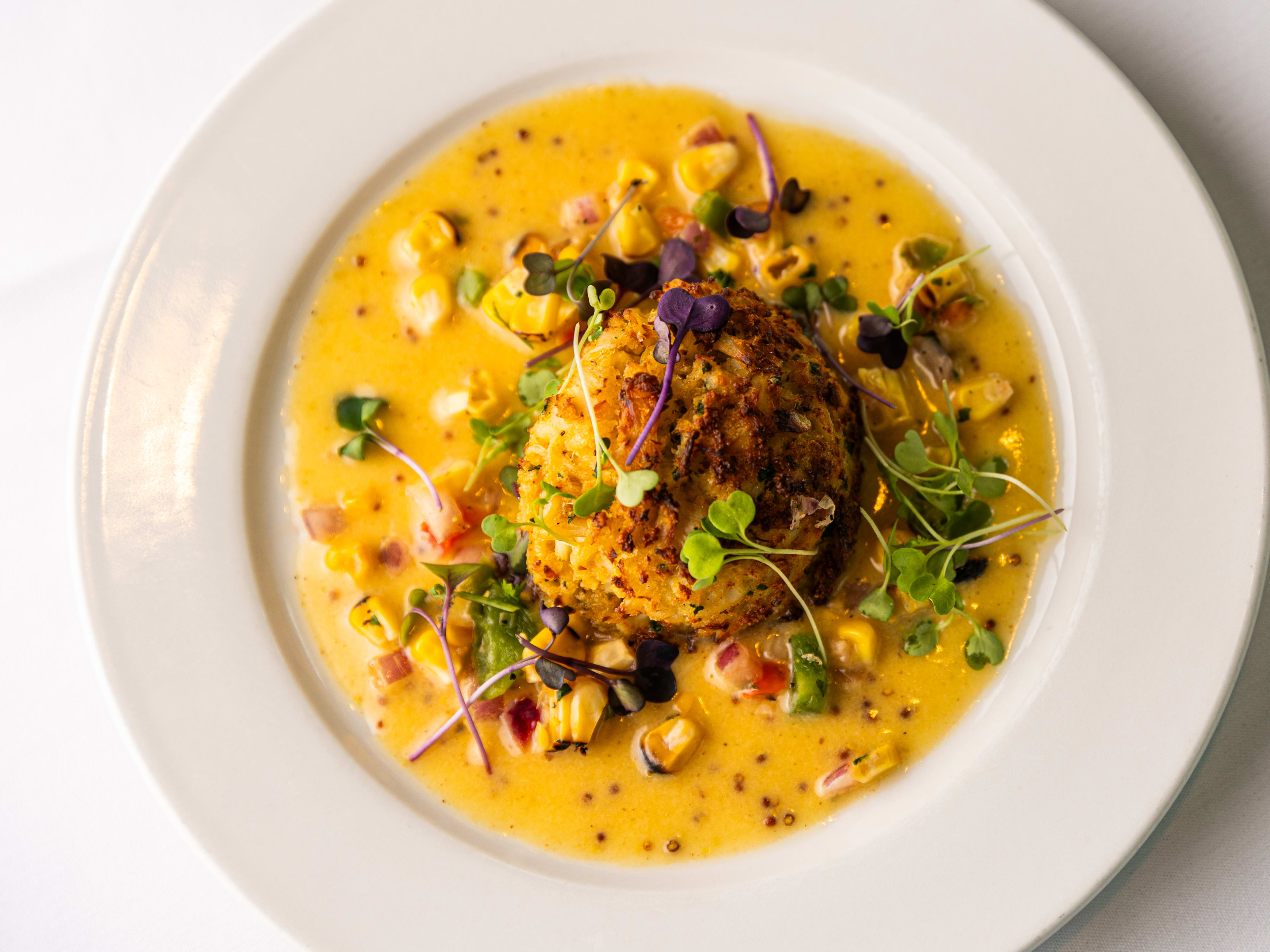 A crab cake surrounded by yellow sauce.