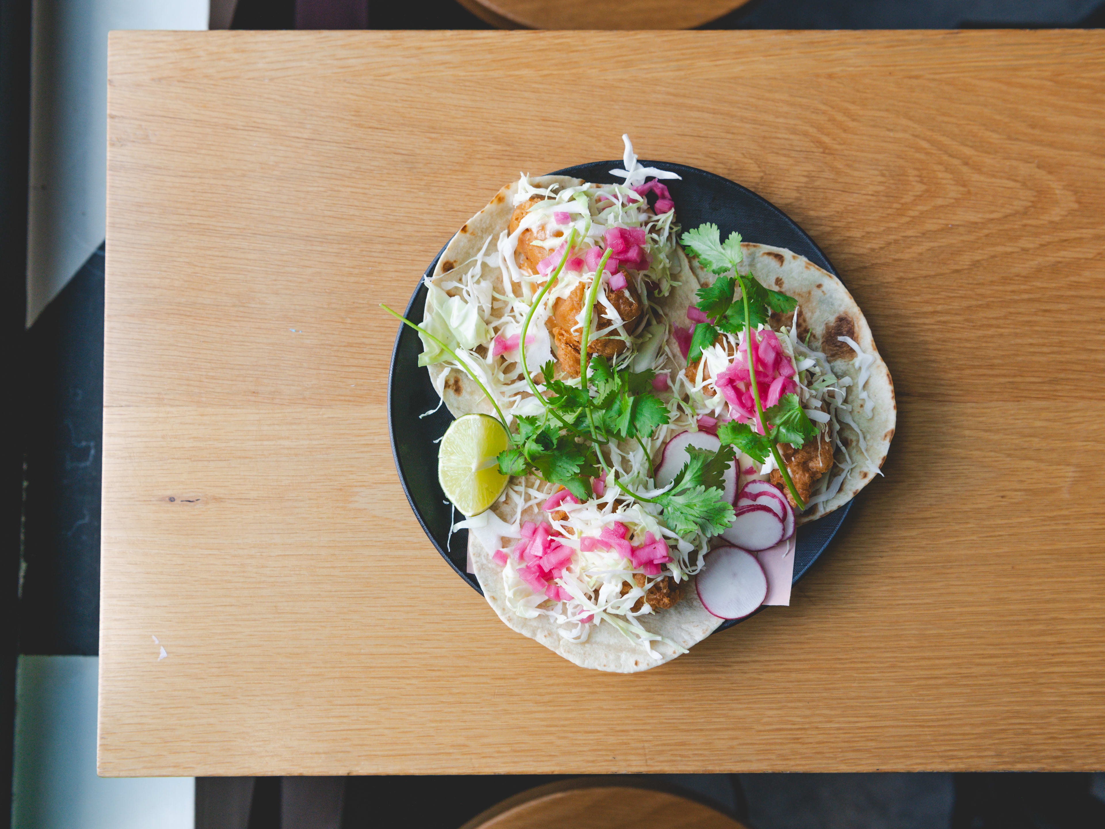 Three fish tacos on a blue plate.