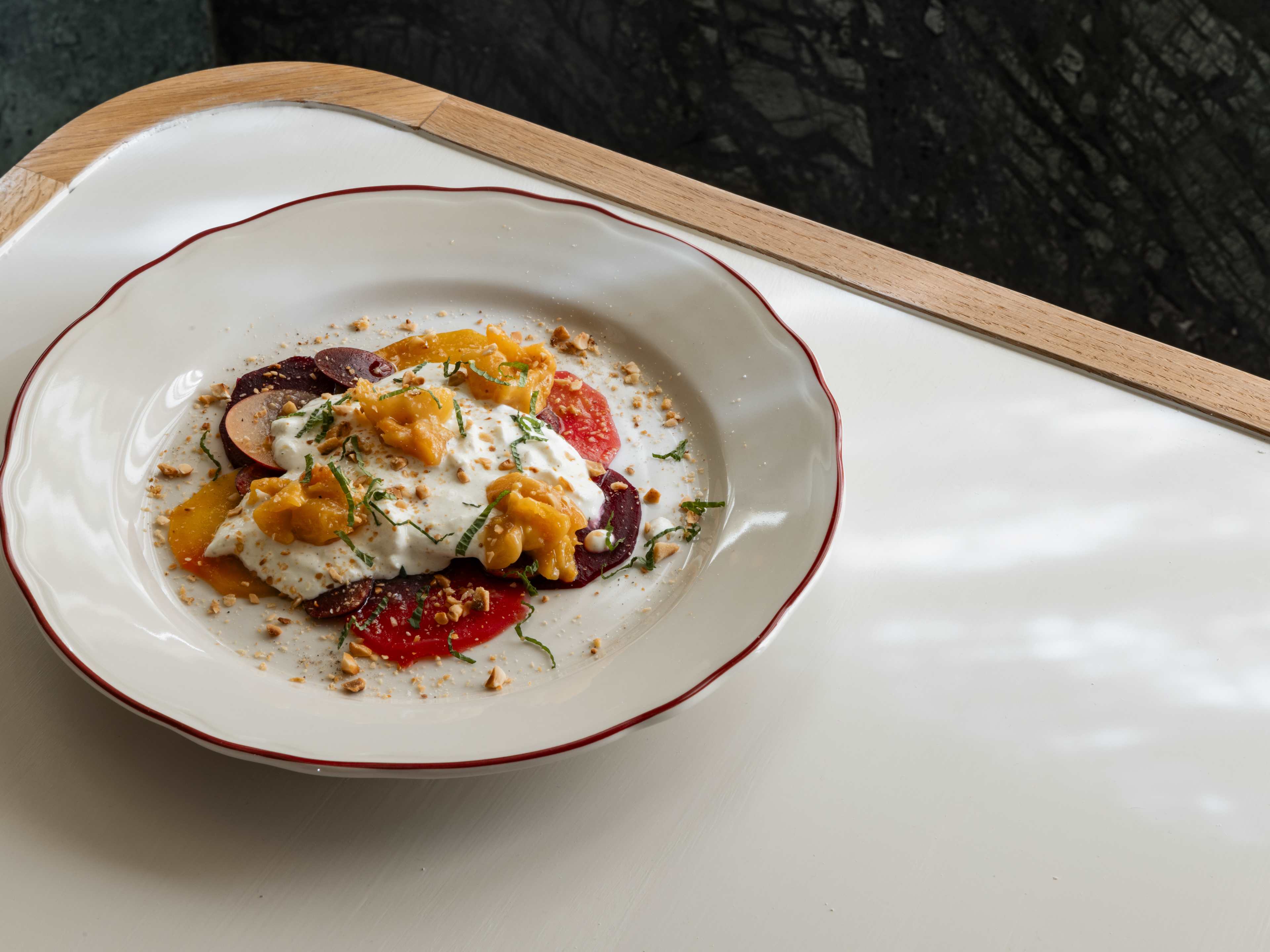 A bowl of straciatella with apricot, beets, and hazelnuts.