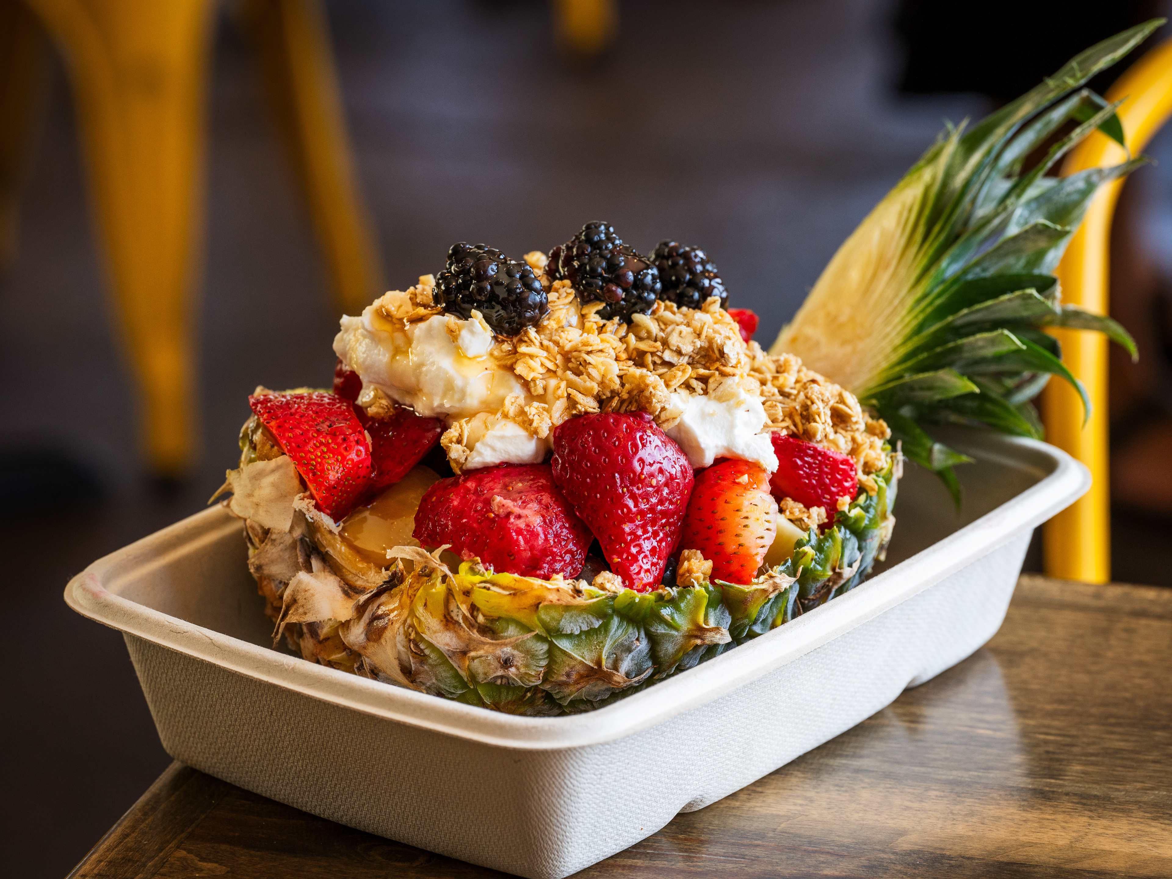 half pineapple topped with yogurt, fruit, and granola