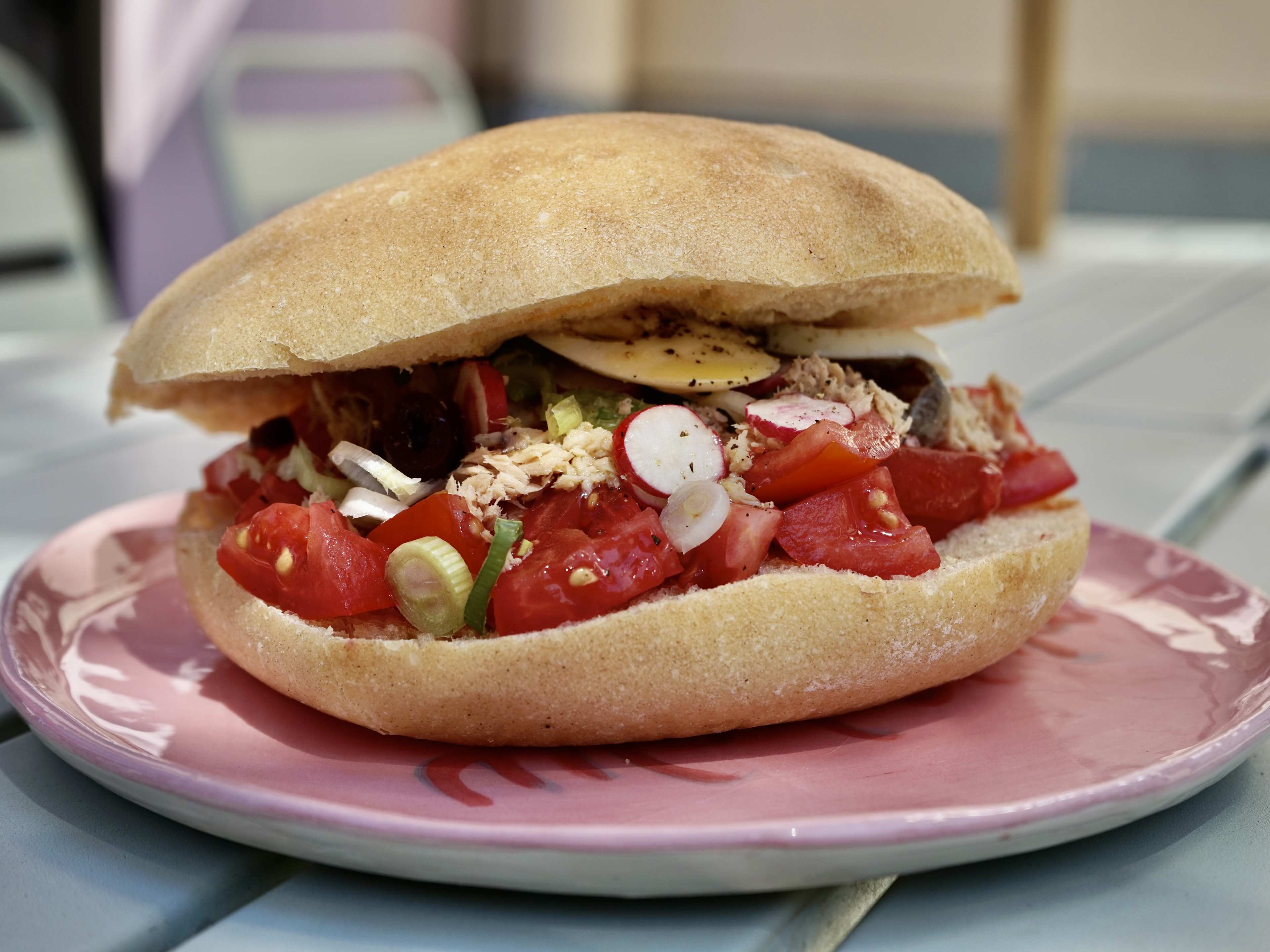 A sandwich stuffed with vegetables on a picnic table outside