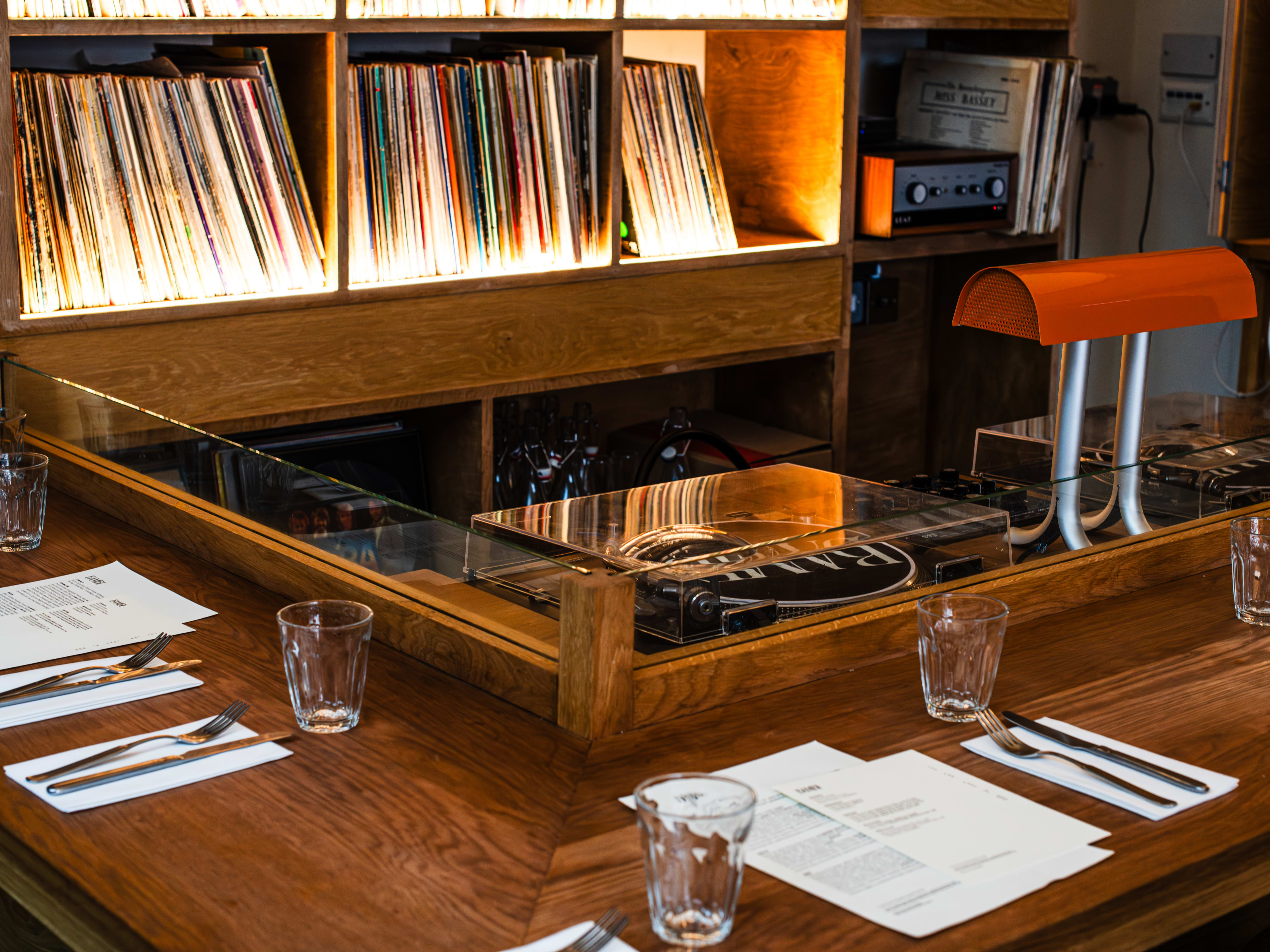 The vinyl booth at Bambi. A record player is behind the bar and vinyls lining shelves on the back wall.