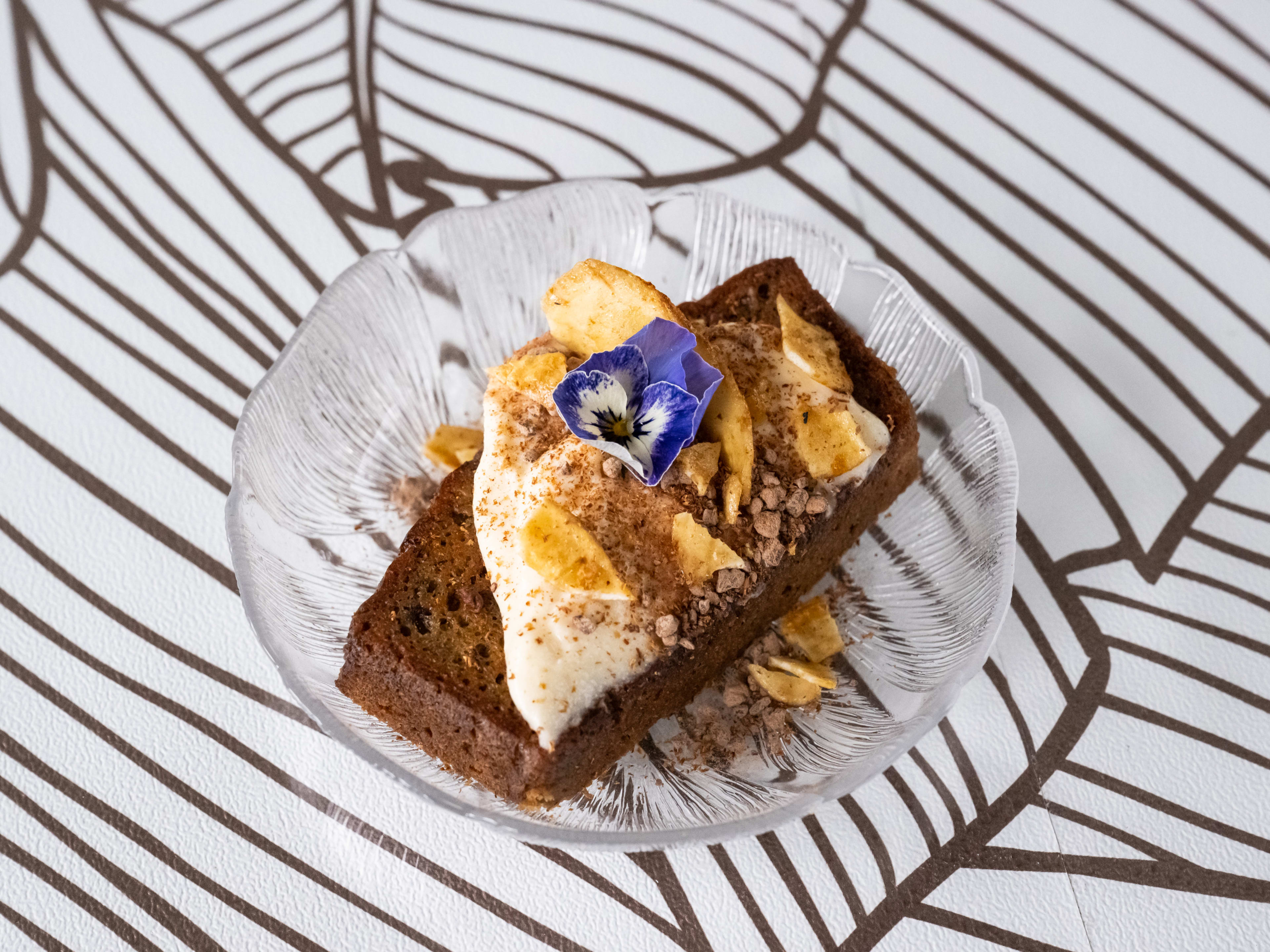 griddled banana bread with latiya, banana chips, ground chocolate, and a blue edible flower