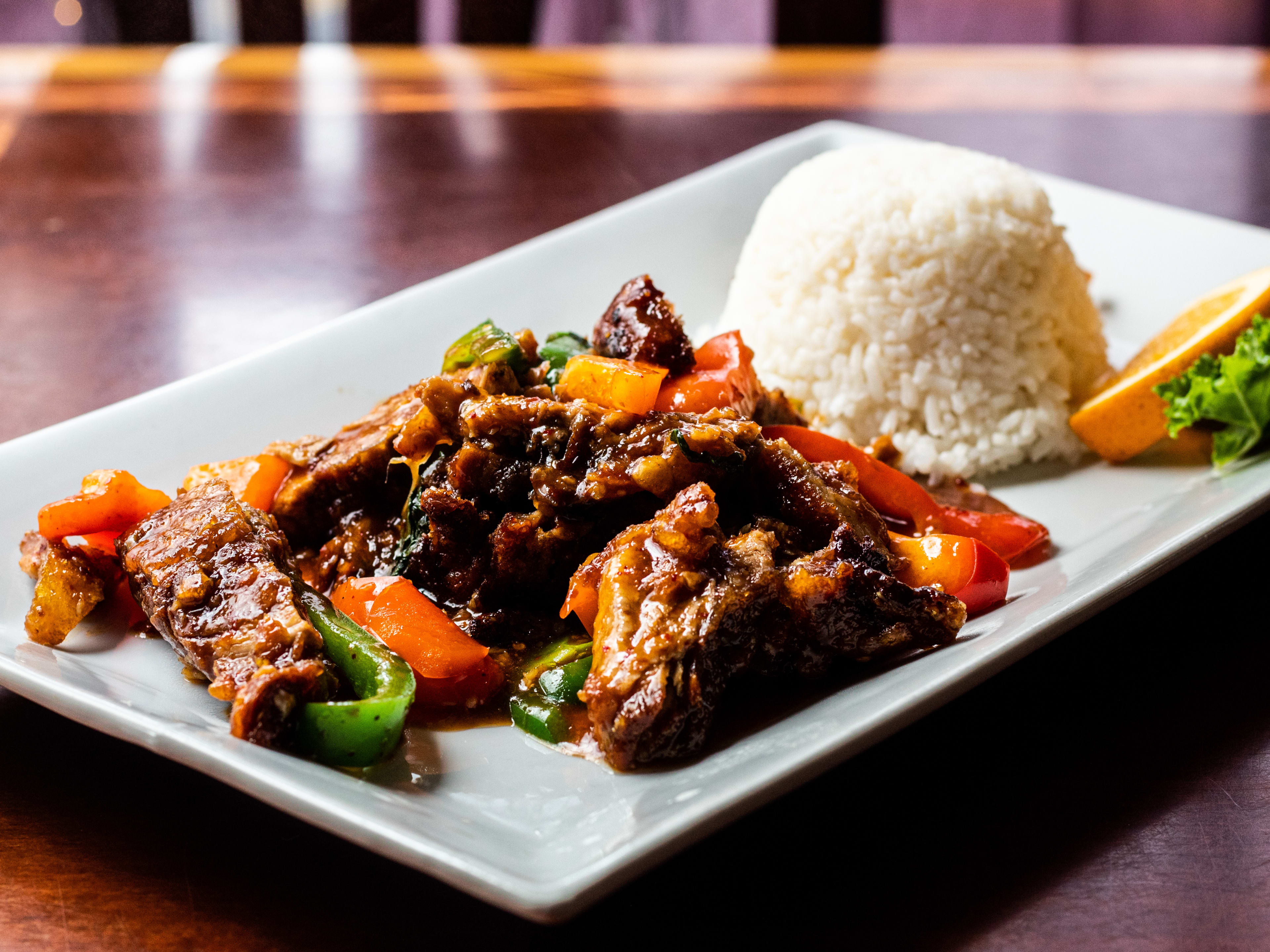 Rectangular plate with beef and pepper stir fry next to a mound of rice