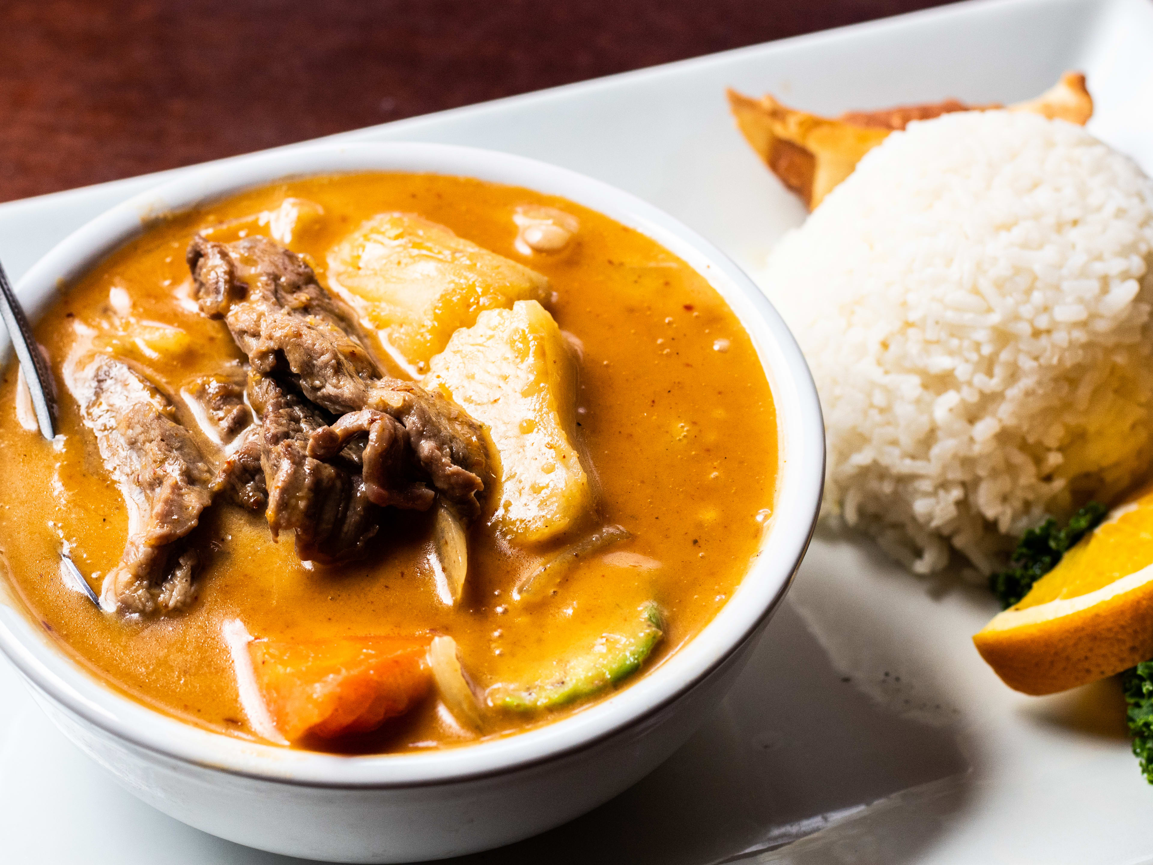 A golden curry with a side of rice on a plate.