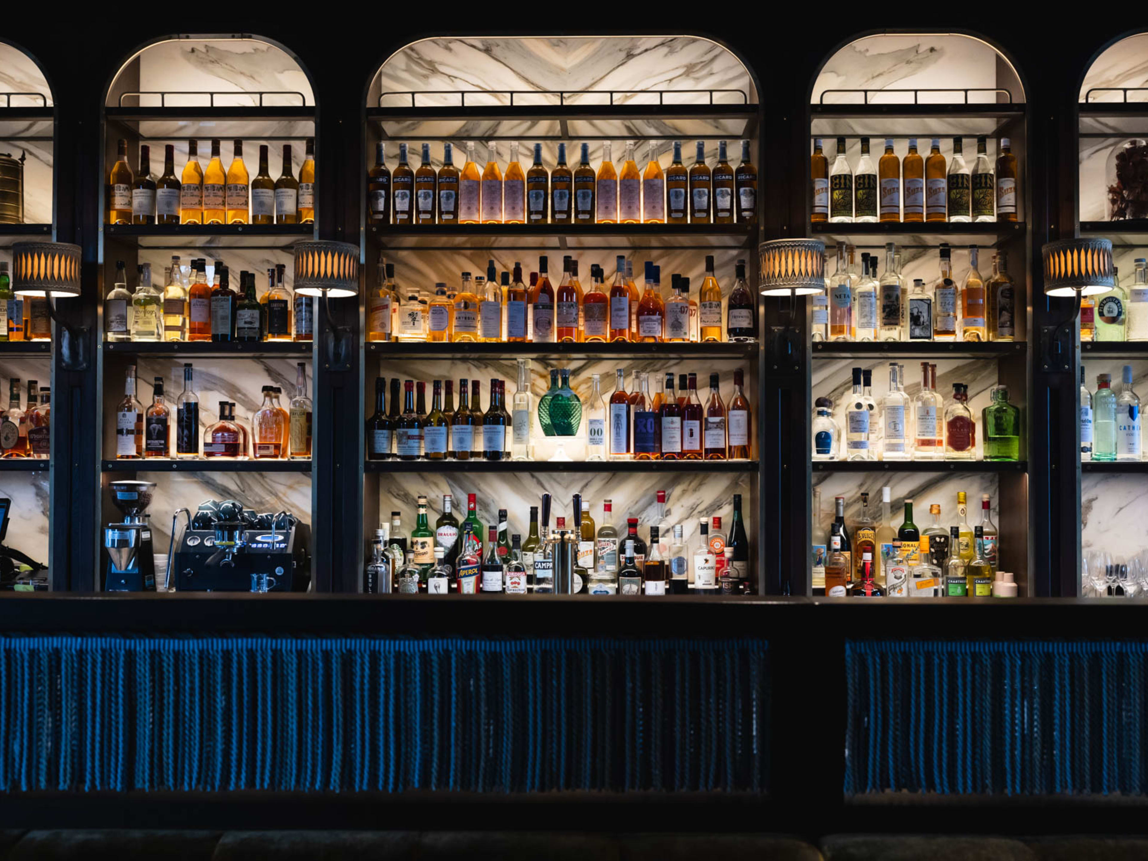 A blue bar with shelves of liquor bottles at Bar Blanc in Atlanta.