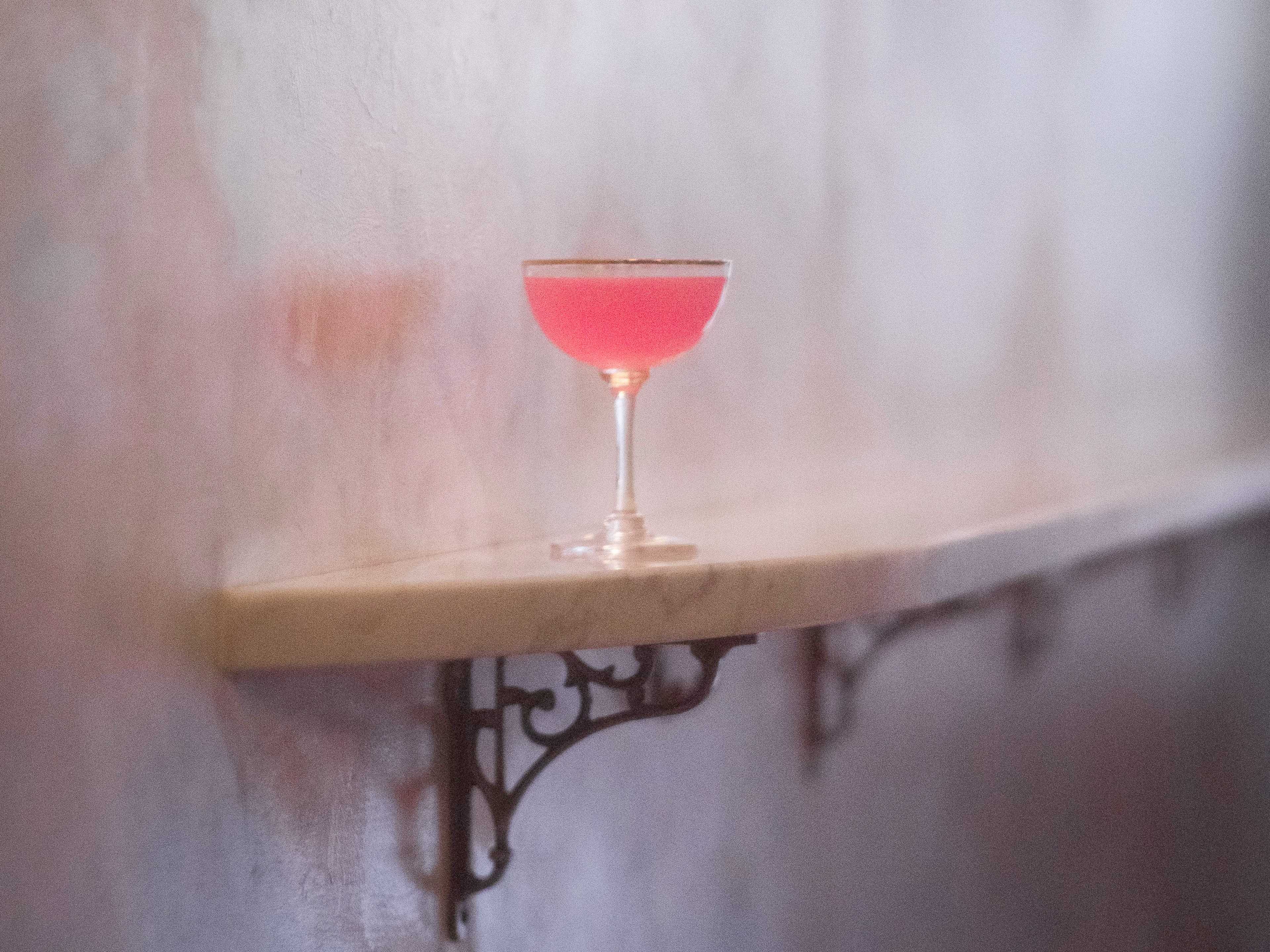 Pink cocktail placed on marble banquette at Bar Nouveau