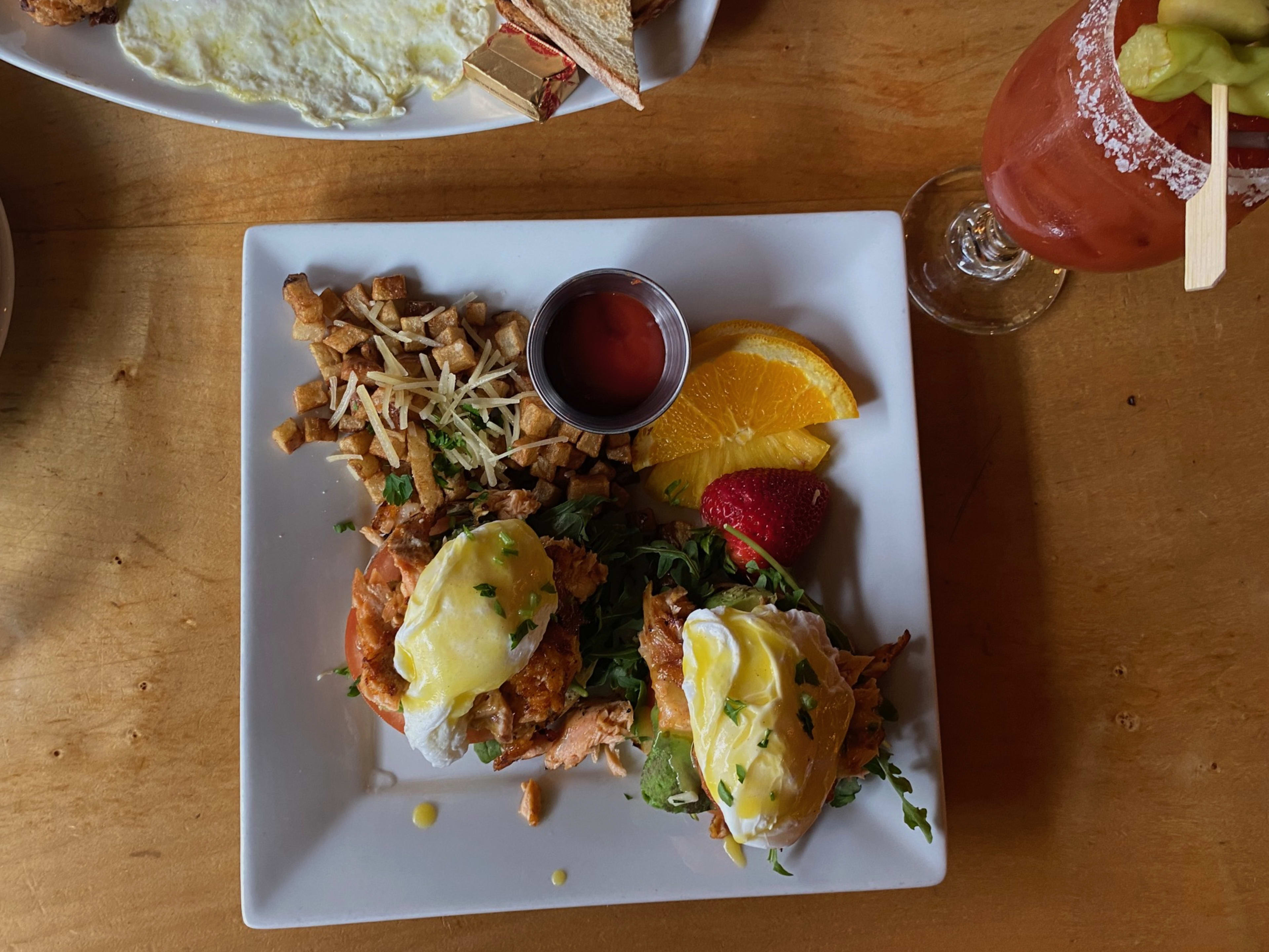 A plate of salmon eggs benedict with a bloody mary on the side