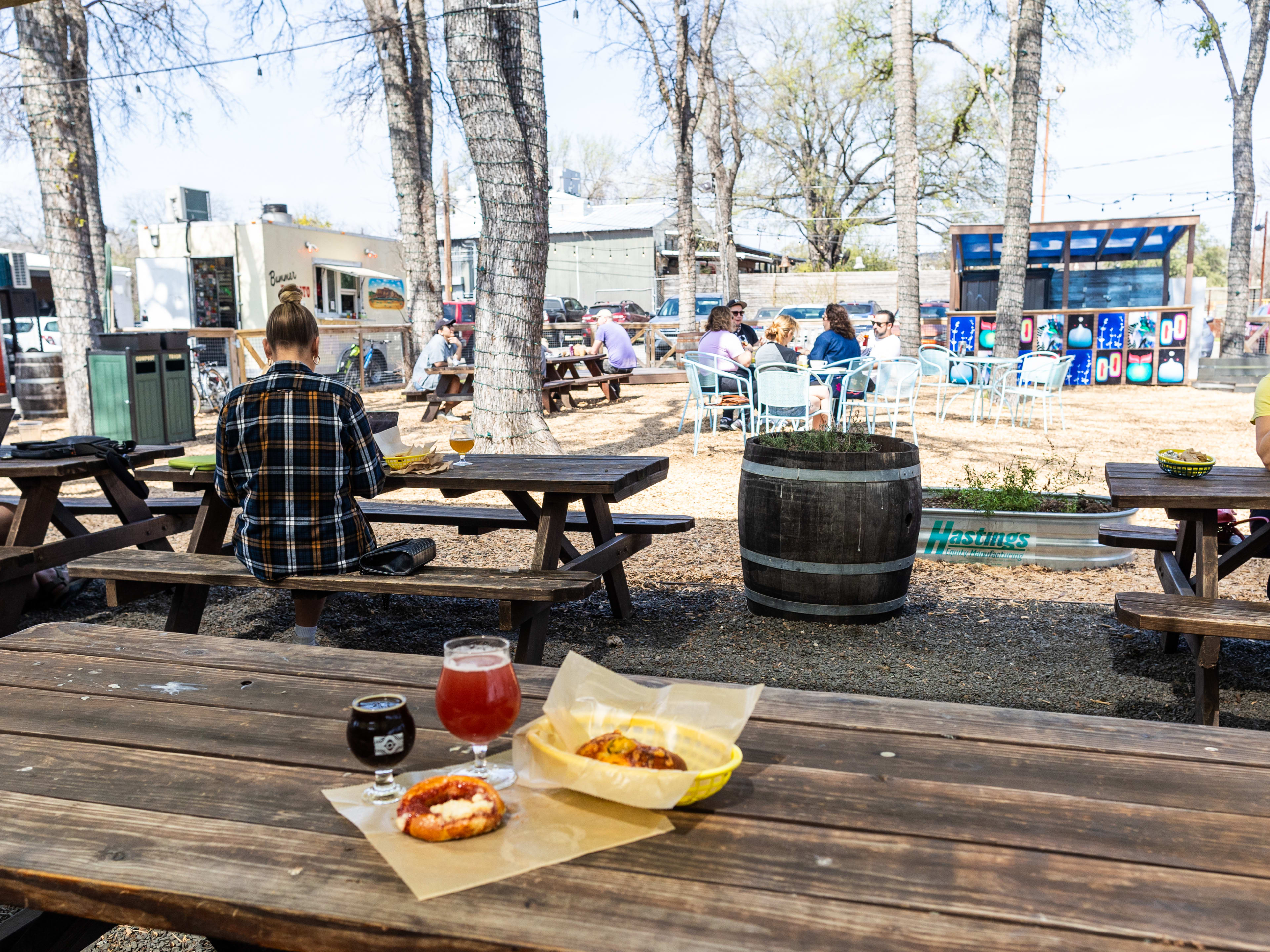 Two beers and two kolaches on a wooden picnic table in the outdoor seating area at Batch Brewing.