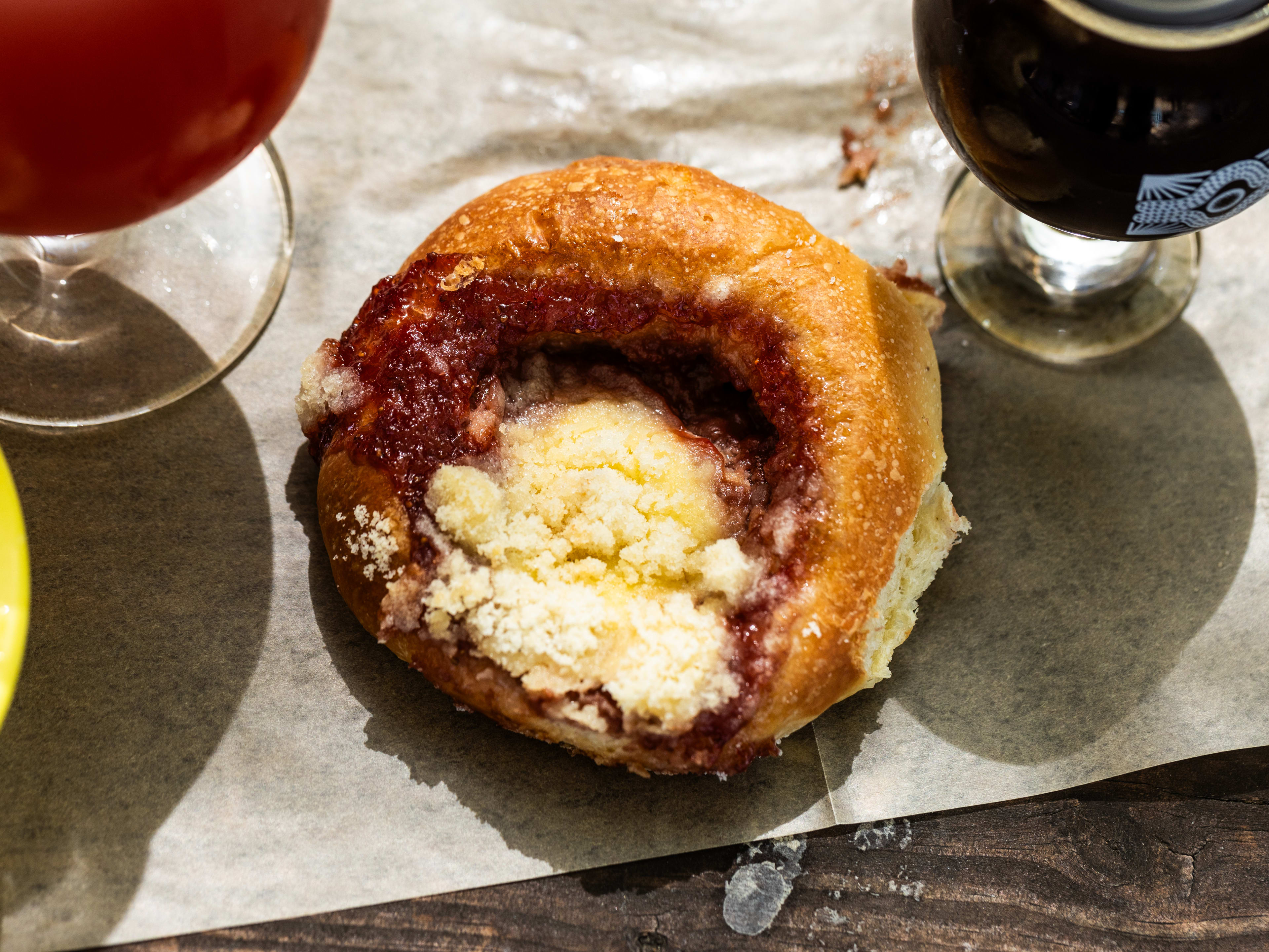 The strawberry kolache from Batch Brewing on parchment paper next to two beers.