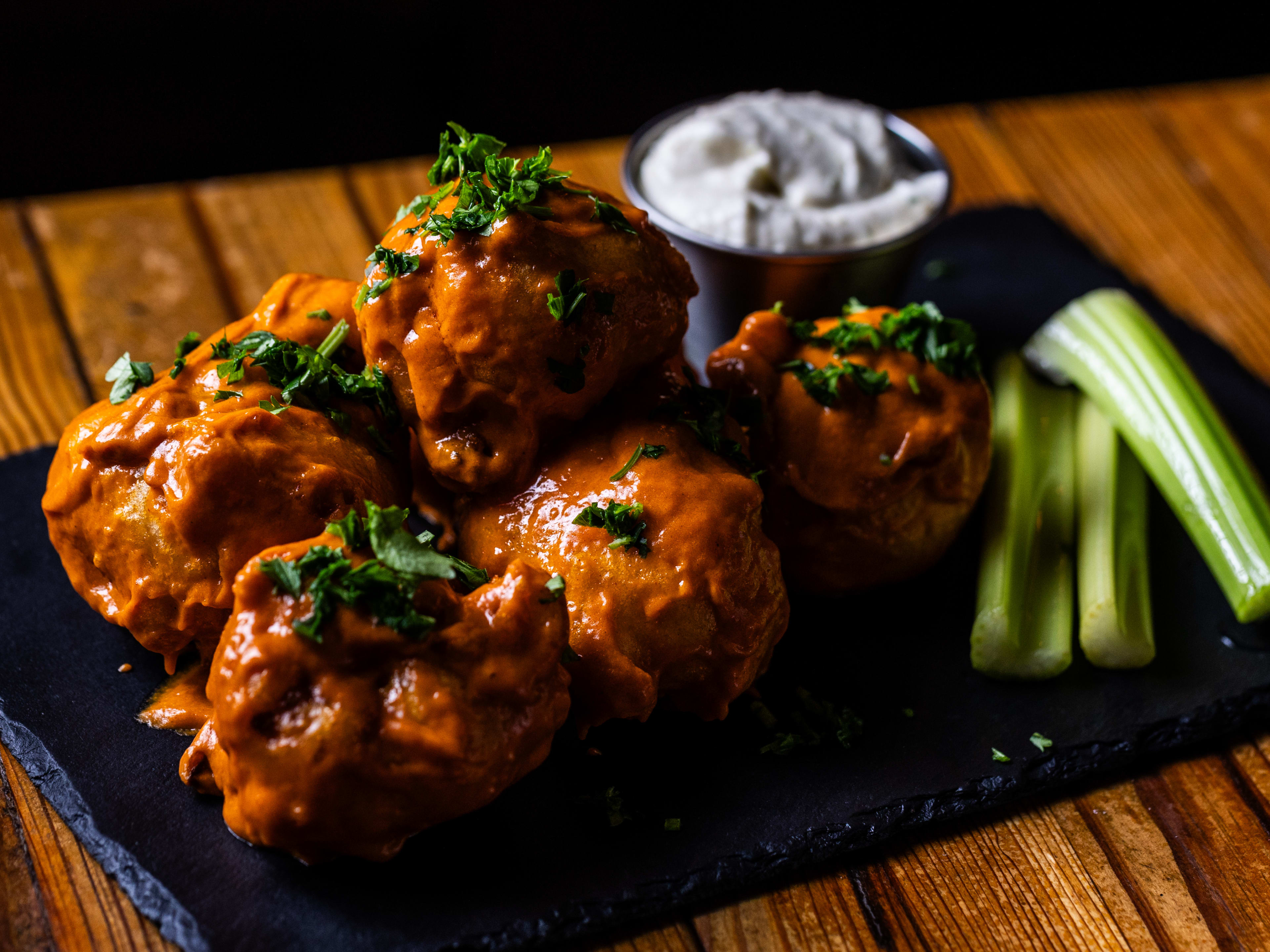 Buffalo cauliflower wings on a slate board on a wooden table.