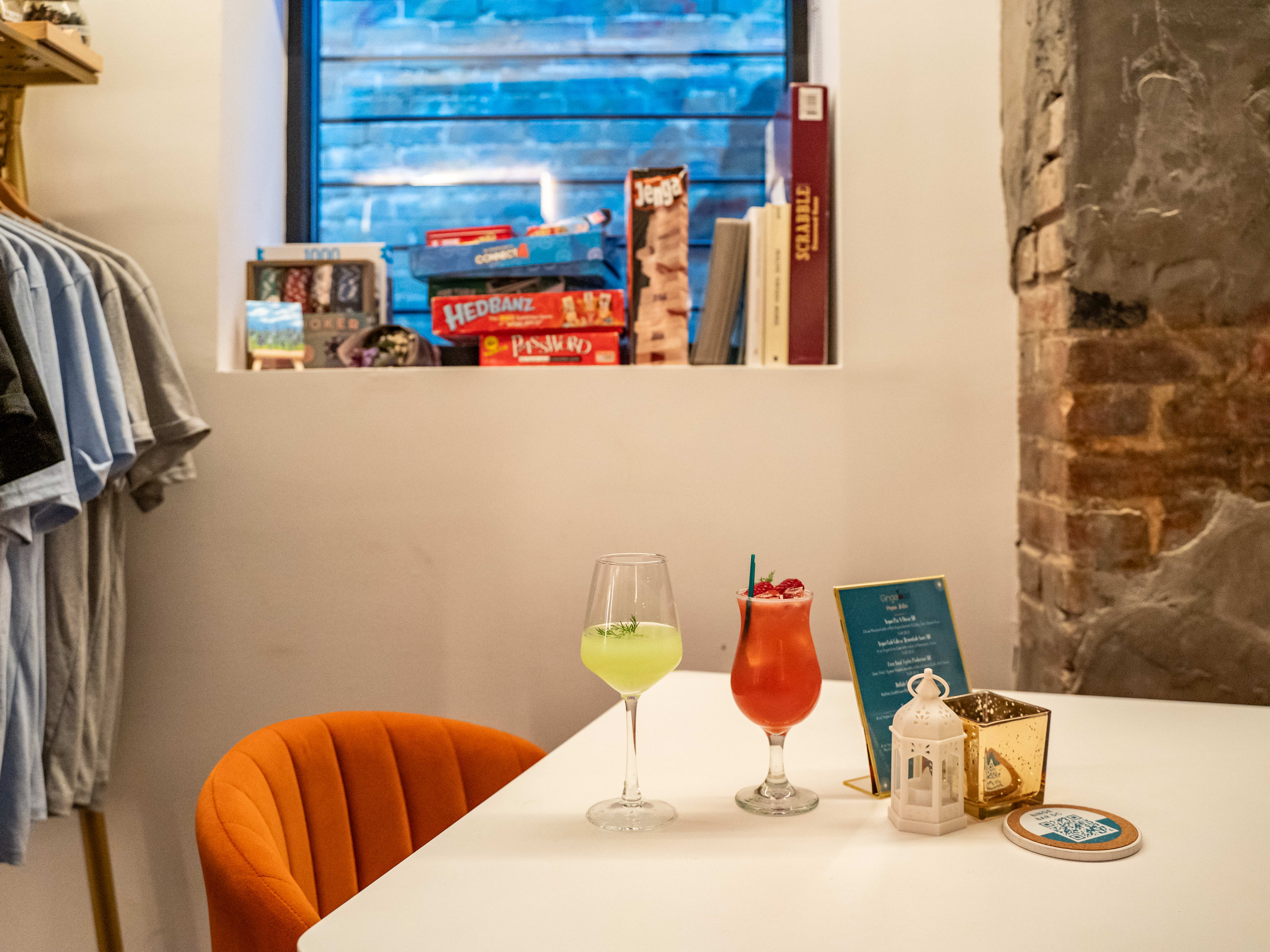 Two colorful drinks on a table with board games lined up in the background