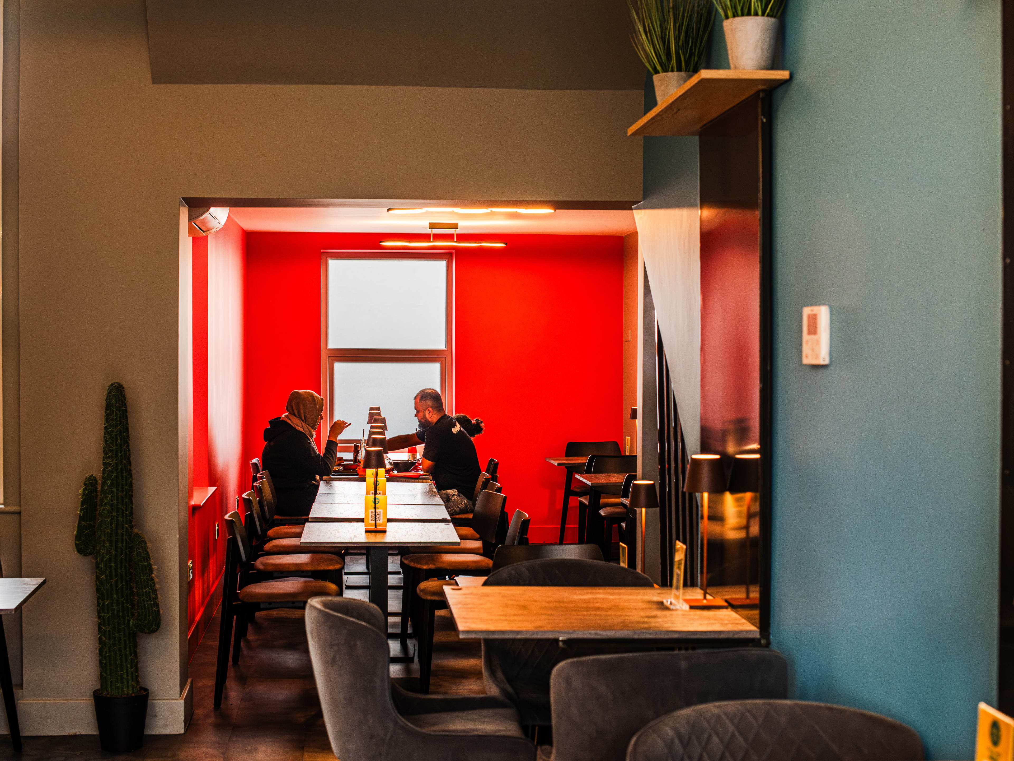 People sitting at a table in the red dining room at Birria Taco.