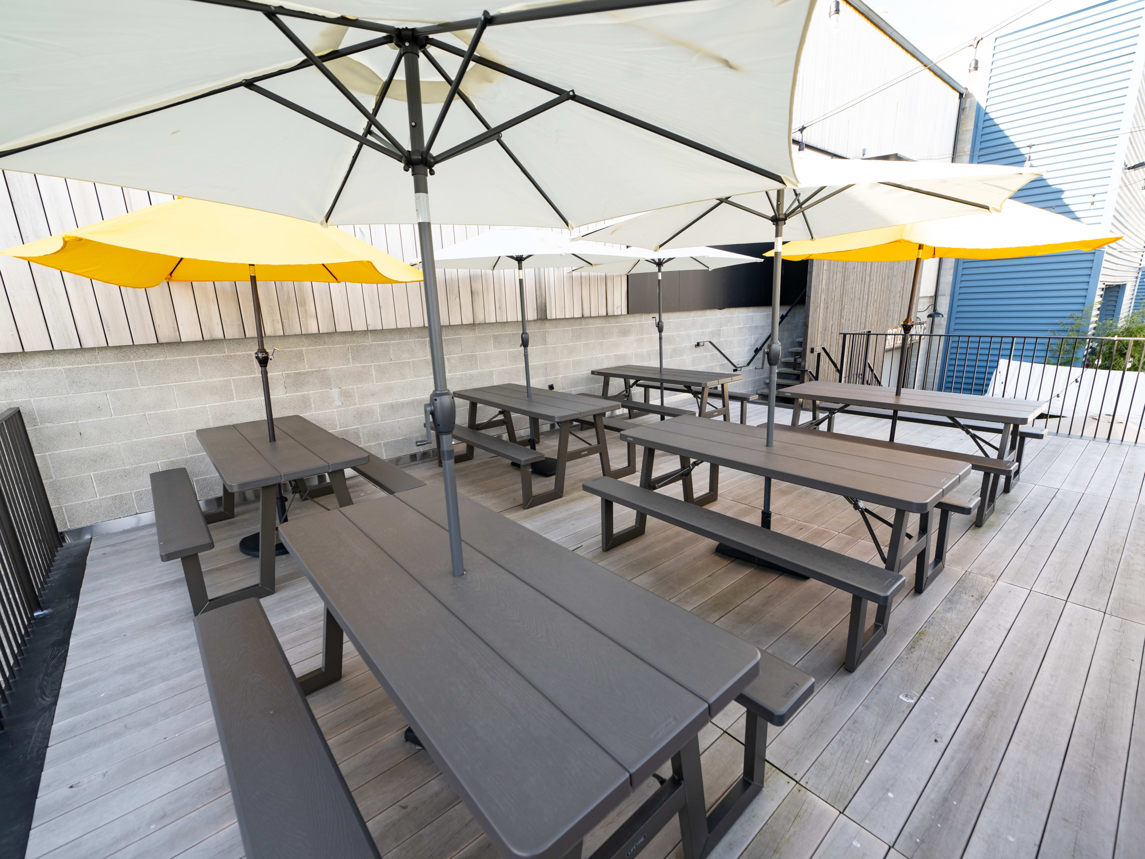 A balcony patio with picnic tables and umbrellas