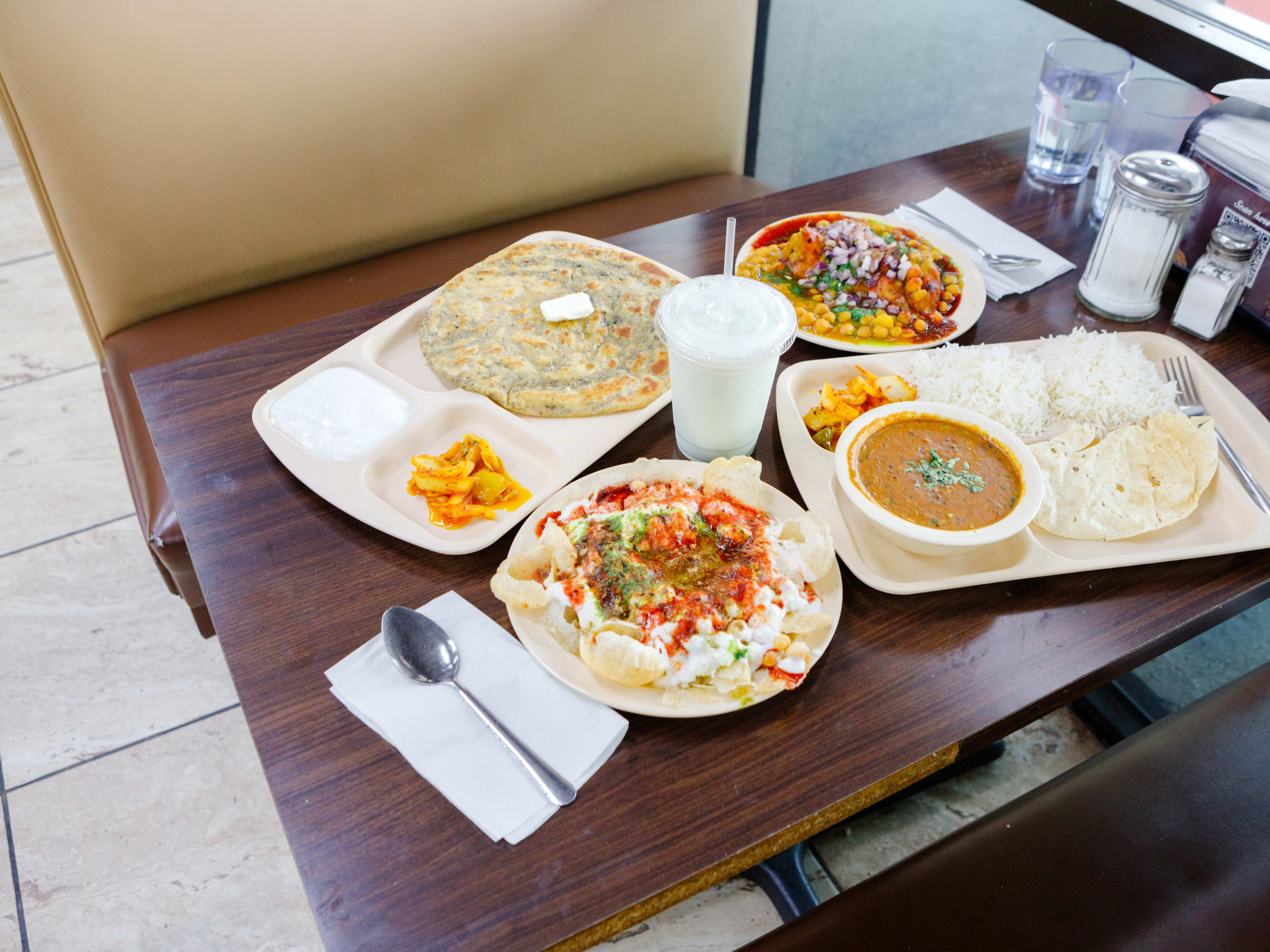 A variety of dishes on a booth table at Bombay Sweets.