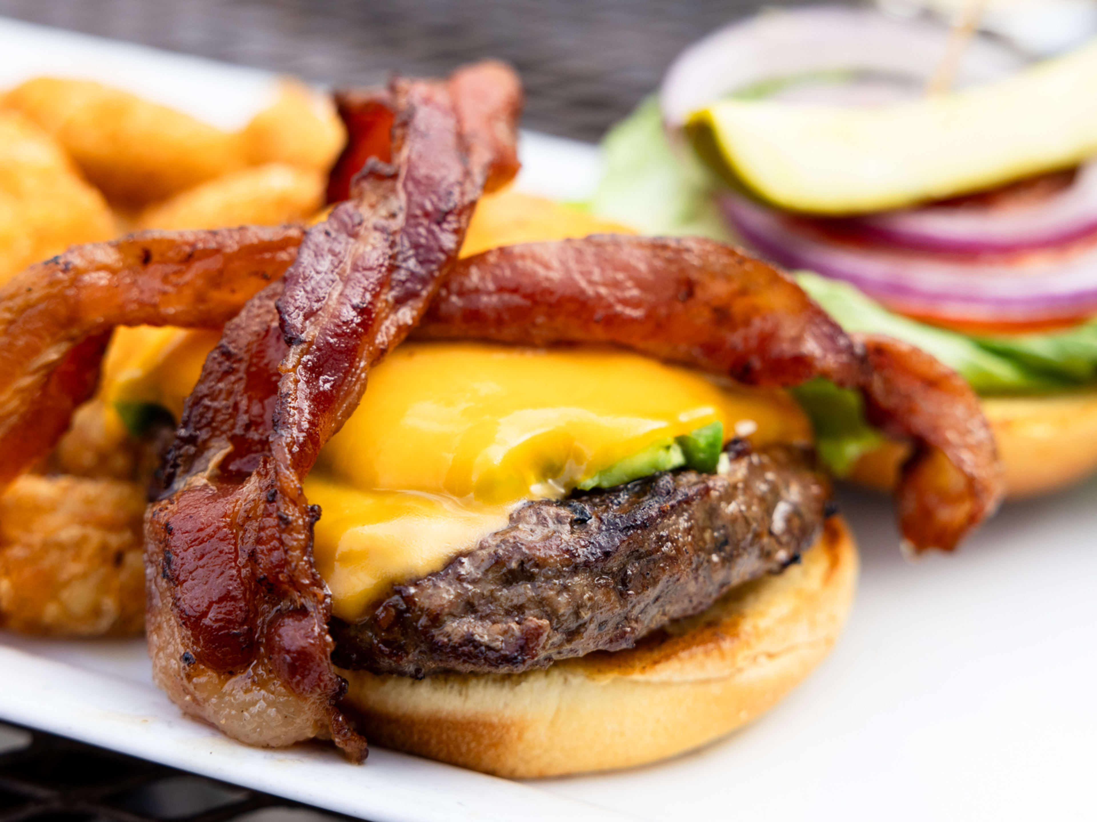 open face cheeseburger with two slices of bacon crossed on top