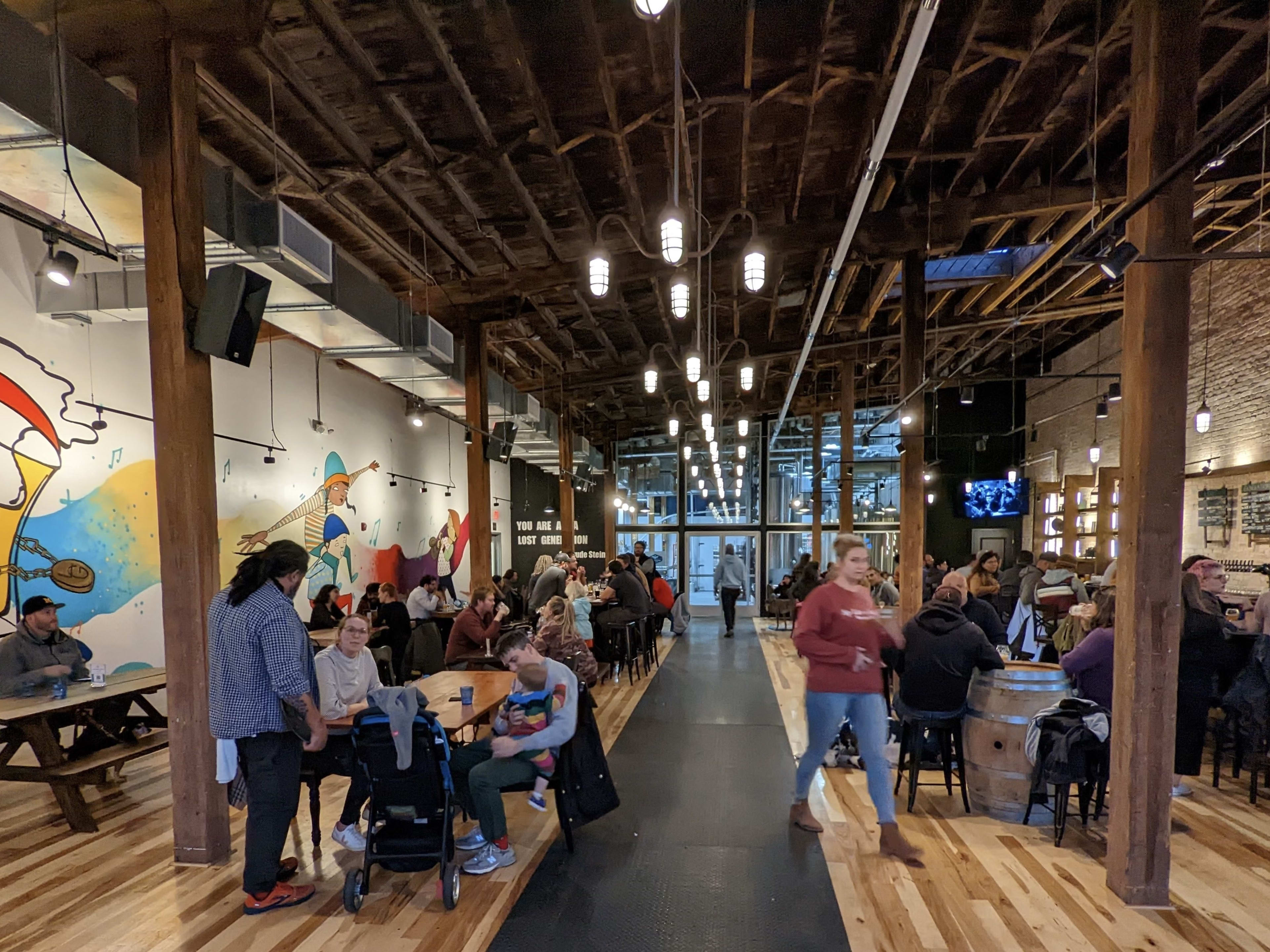 interior of brewery with colorful mural and people sitting at tables