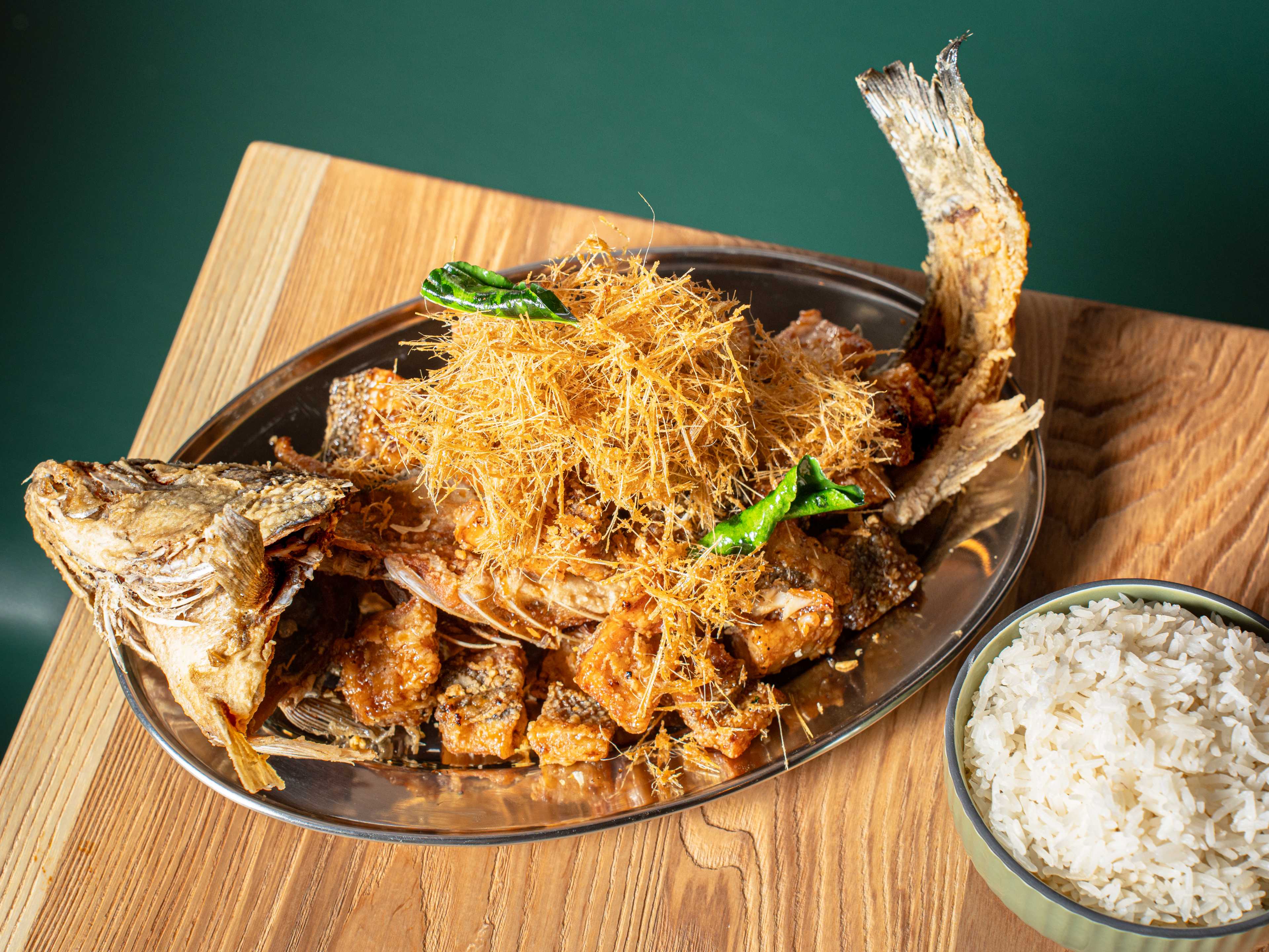 branzino tod num pla on a plate with the fried tail and head curling up