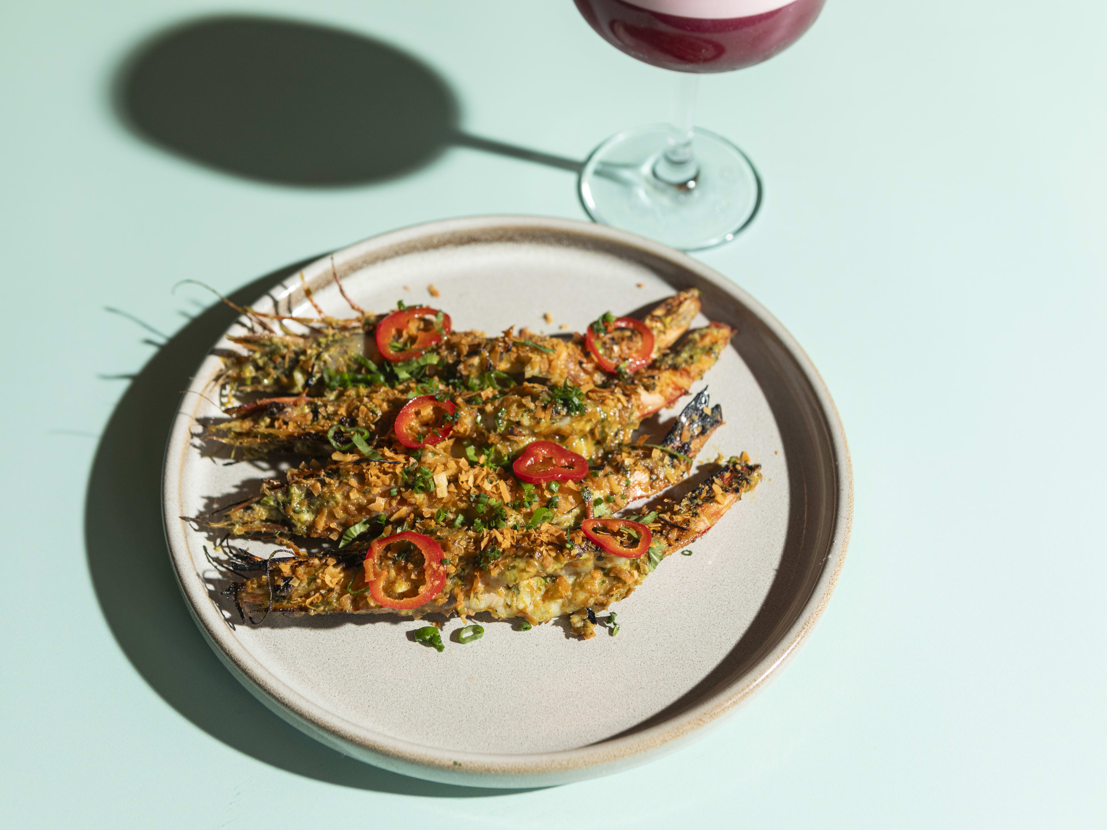 Four fried chili prawns lined up on a plate