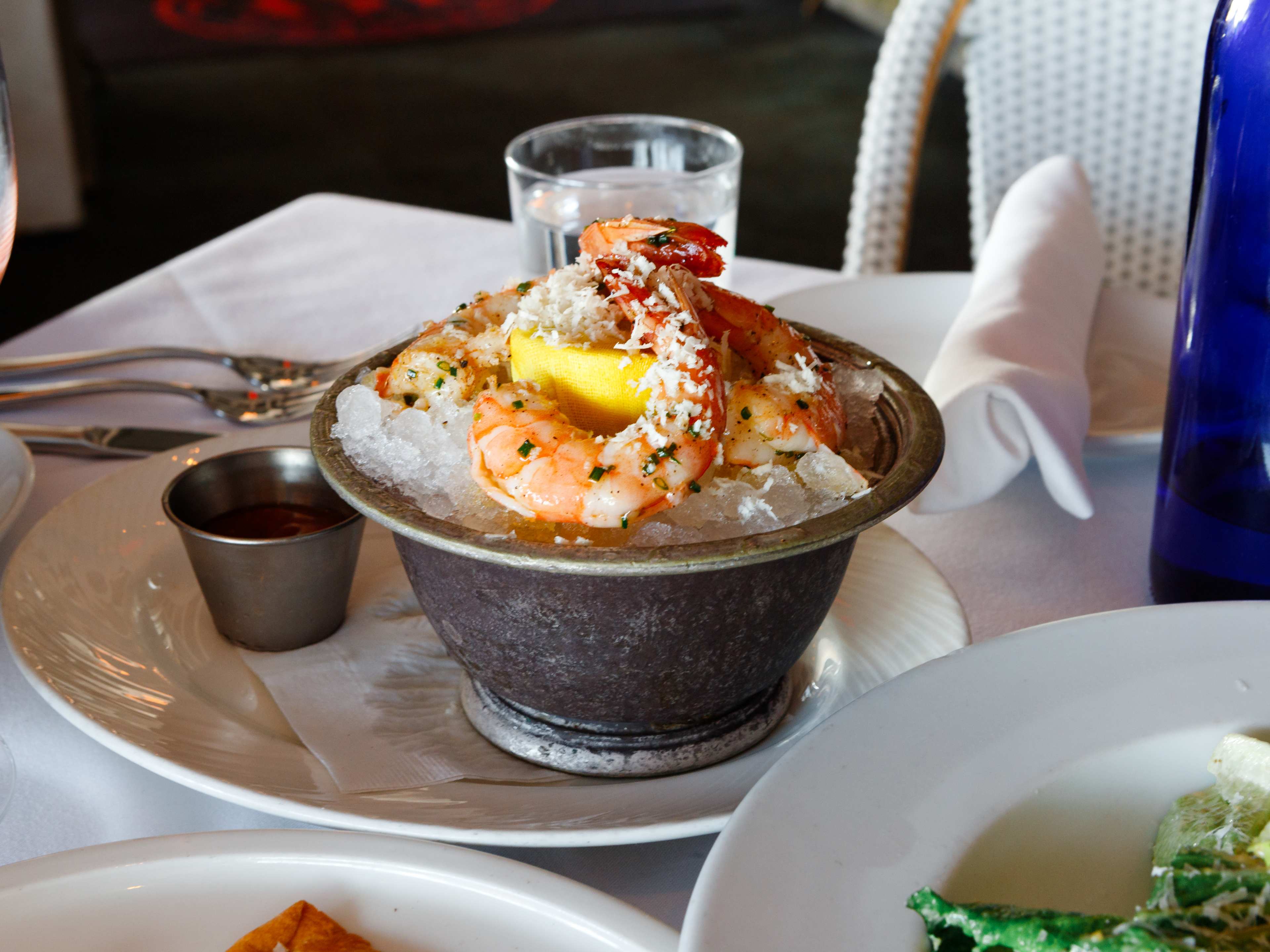 pewter bowl filled with pebble ice with jumbo shrimp cocktail dressed in herbs sitting on top