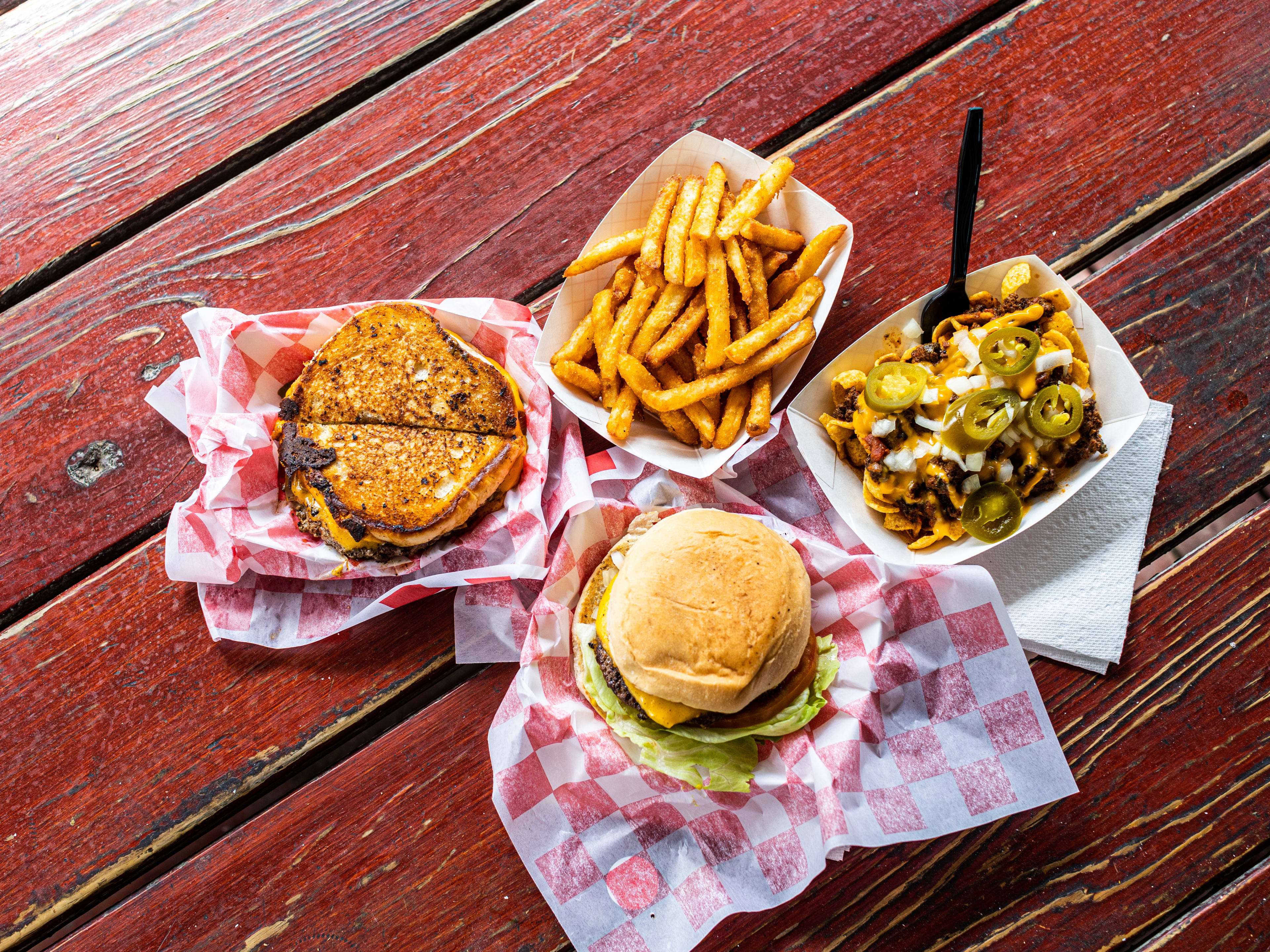 A spread of dishes from Bubba's Texas Burger Shack on a red picnic table.