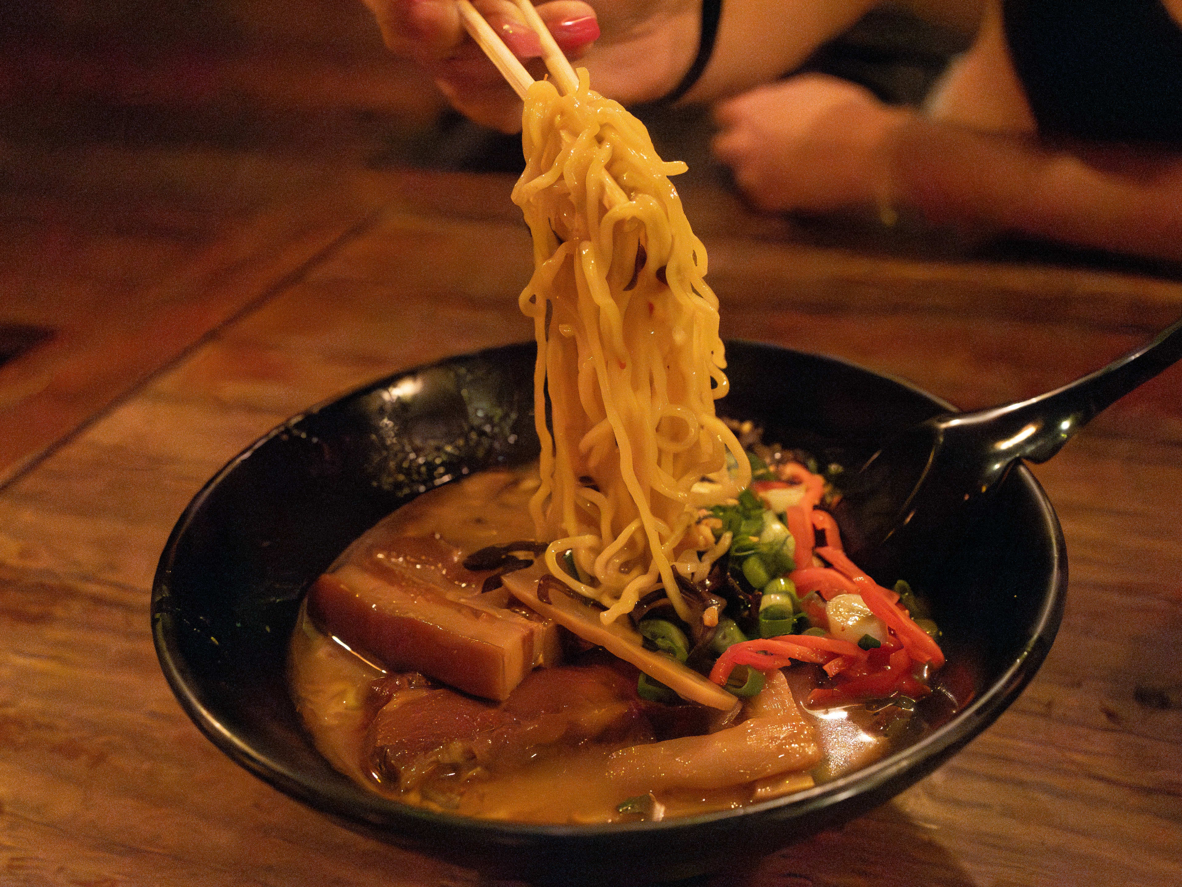 Someone pulls noodles out of a bowl of ramen at Coco's