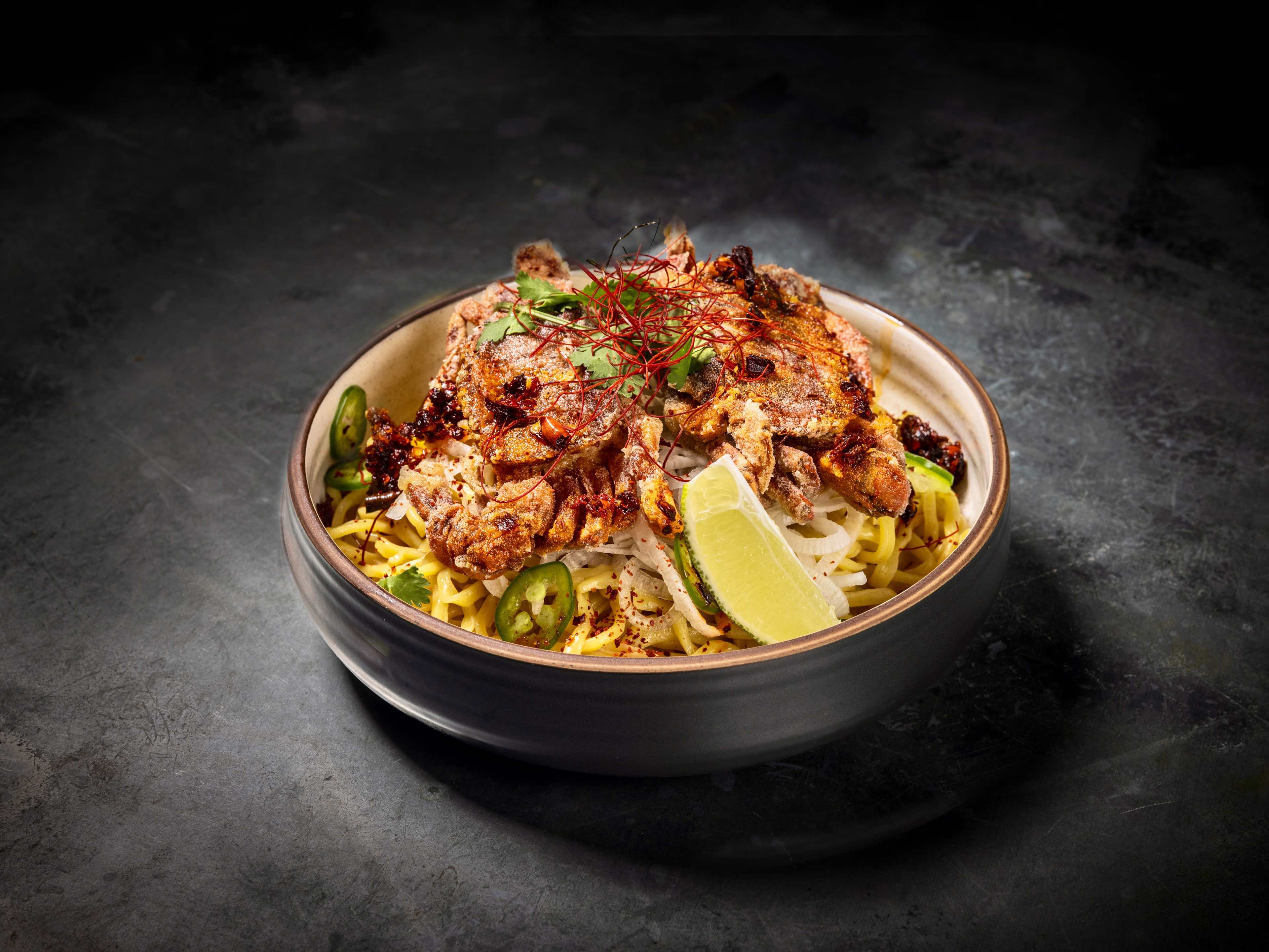 a noodle dish with a fried softshell crab on top