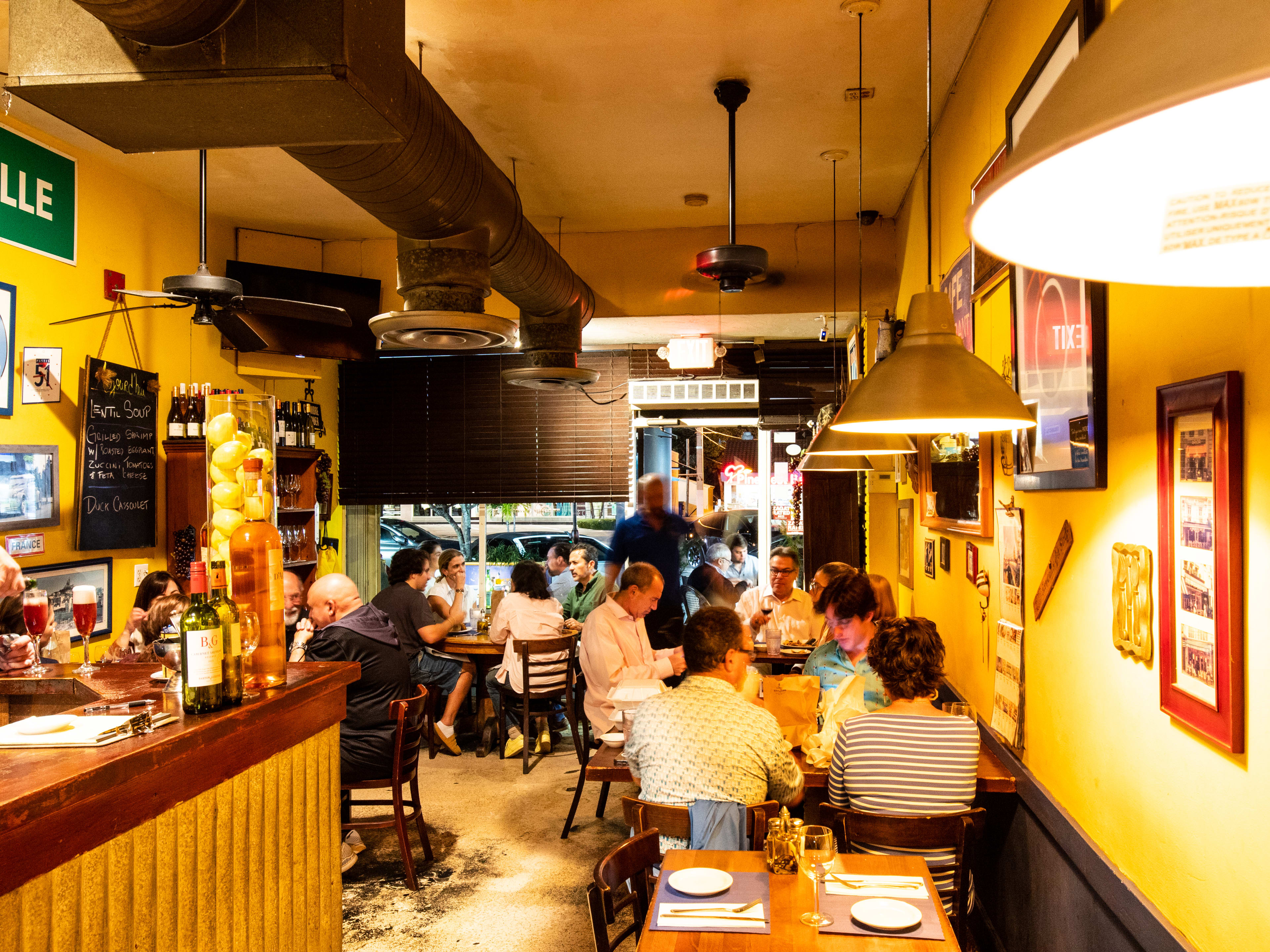 the interior of a restaurant with yellow walls, picture frames of various sizes, and french memorabilia all around the space.