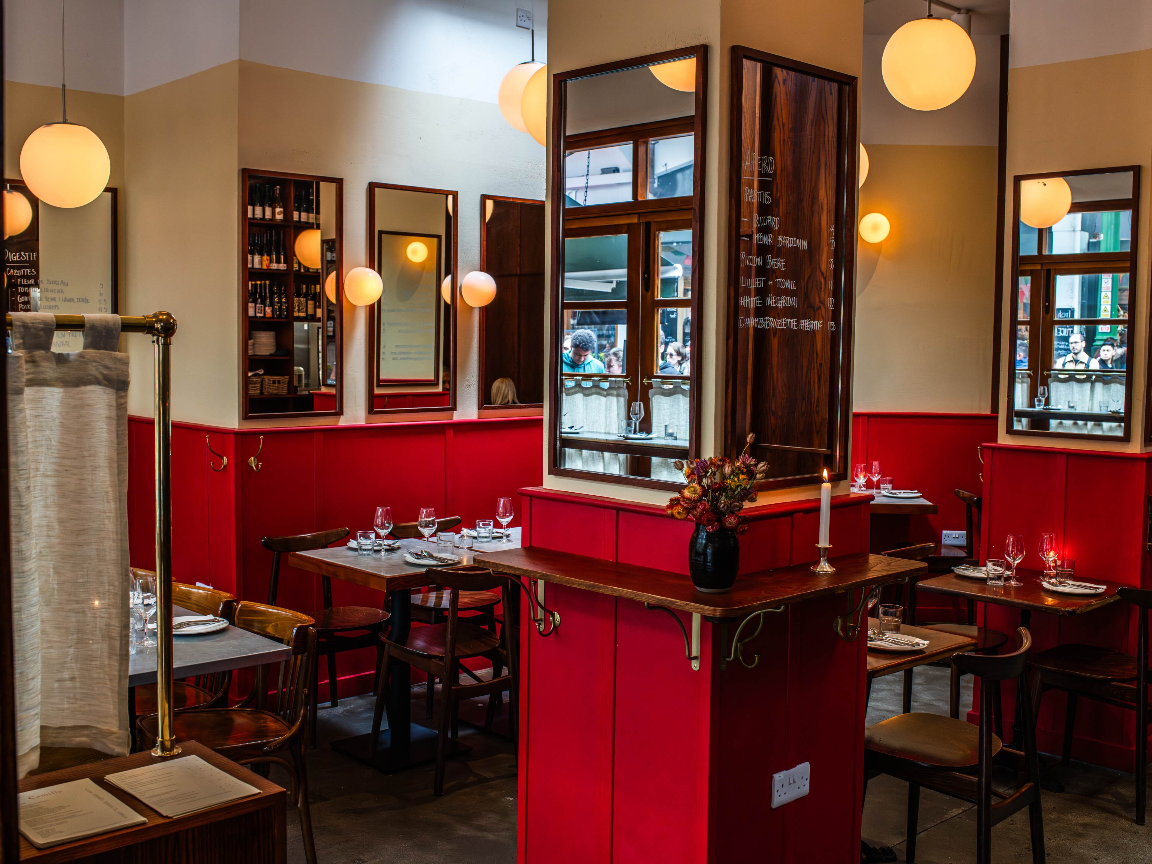 The view as you enter Camille in Borough Market, complete with candles, red hinted walls, and hand written menus on mirrors.