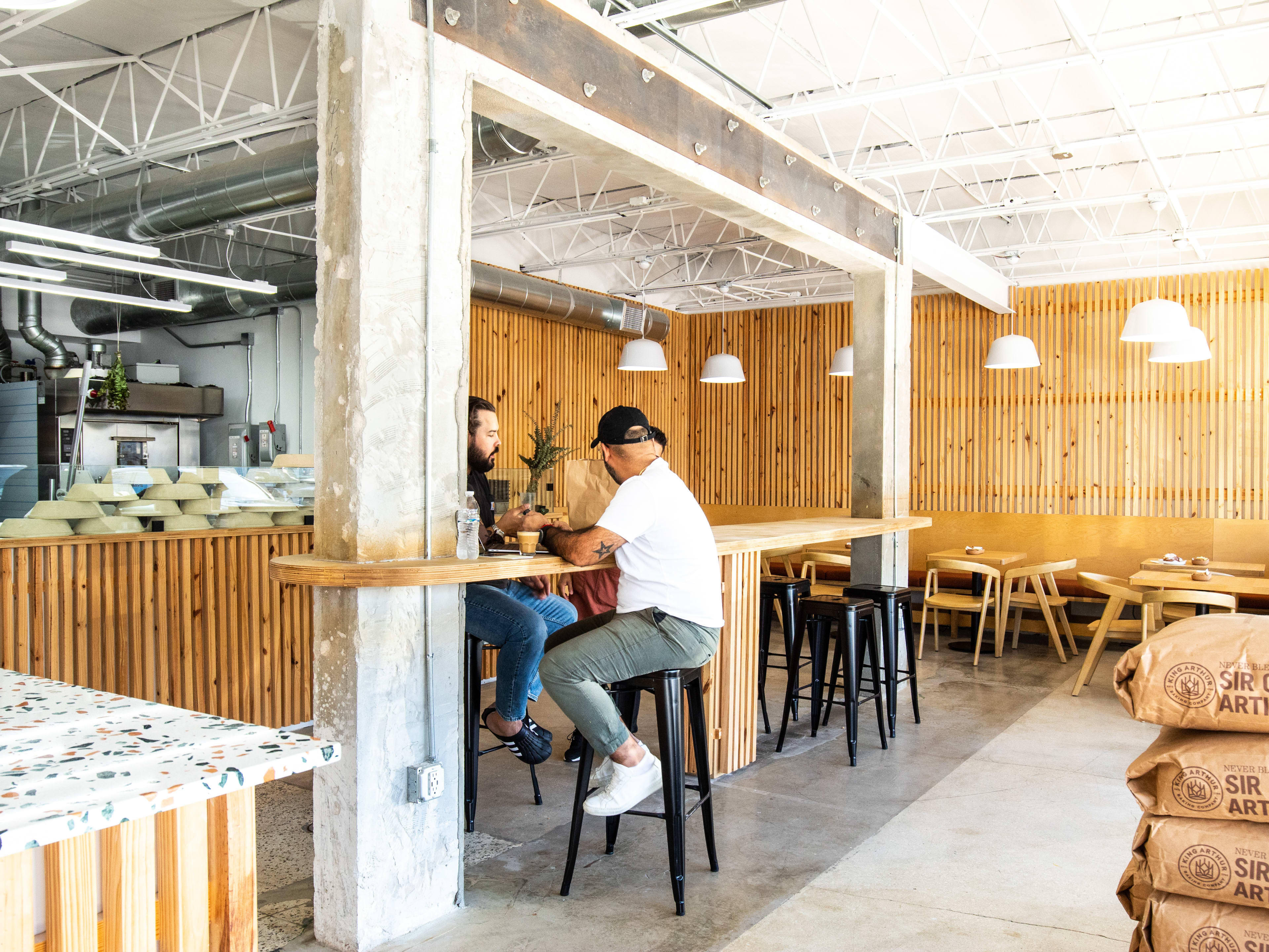 Two people sit at tables inside a wooden bakery.