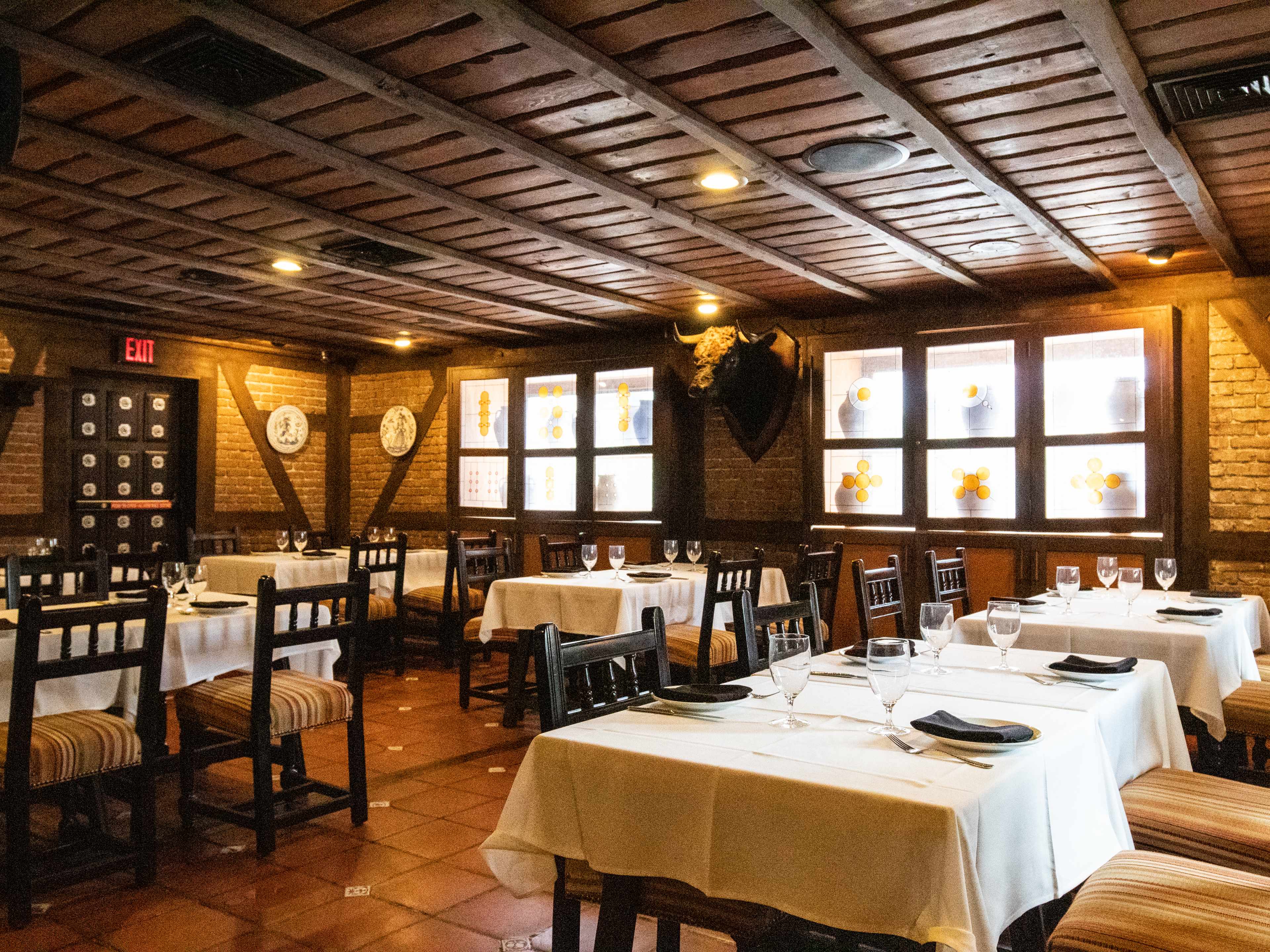 interior of spanish restaurant with low wood ceilings and tables with tableclothes