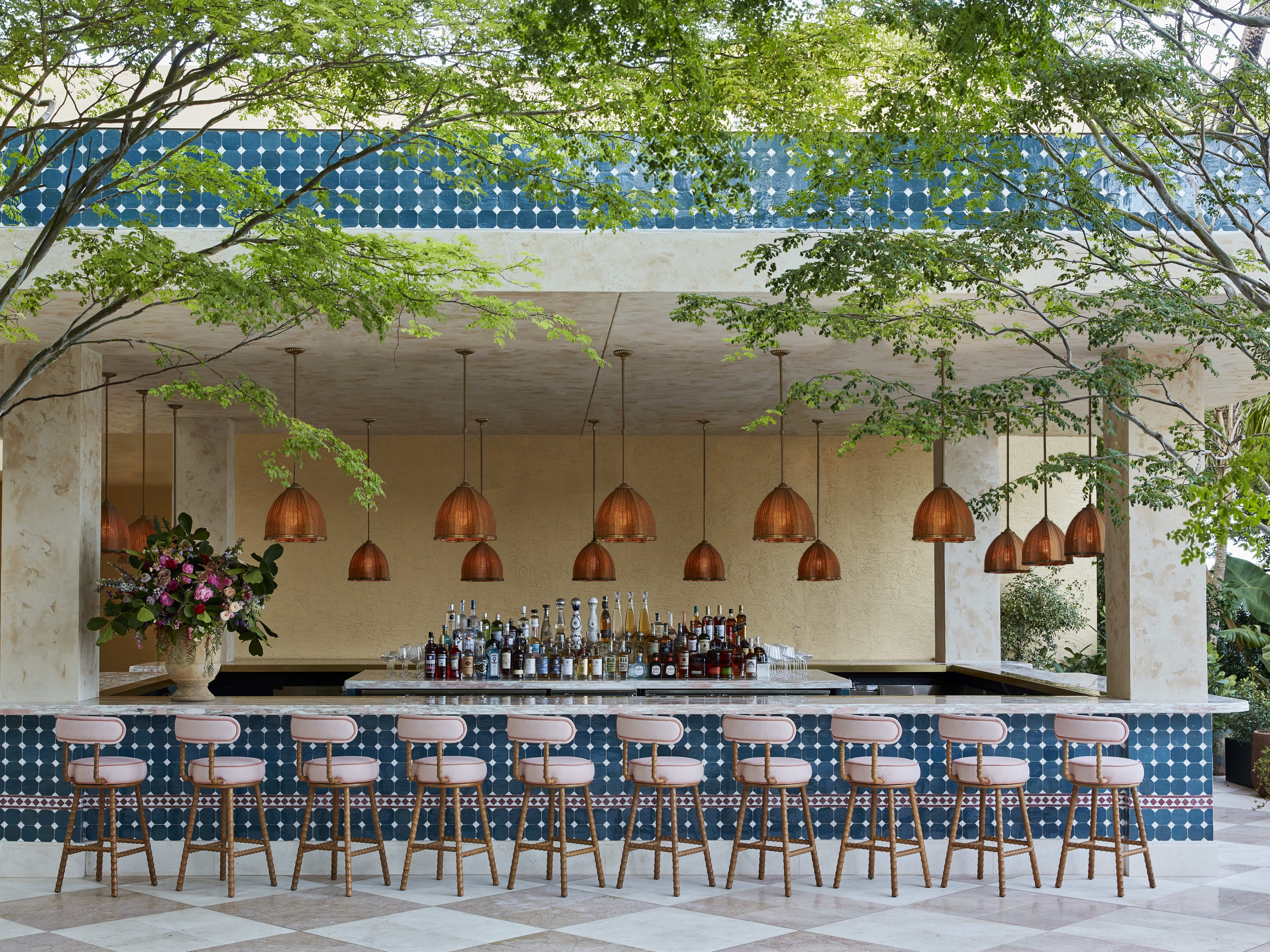 An outdoor bar with pink stools.