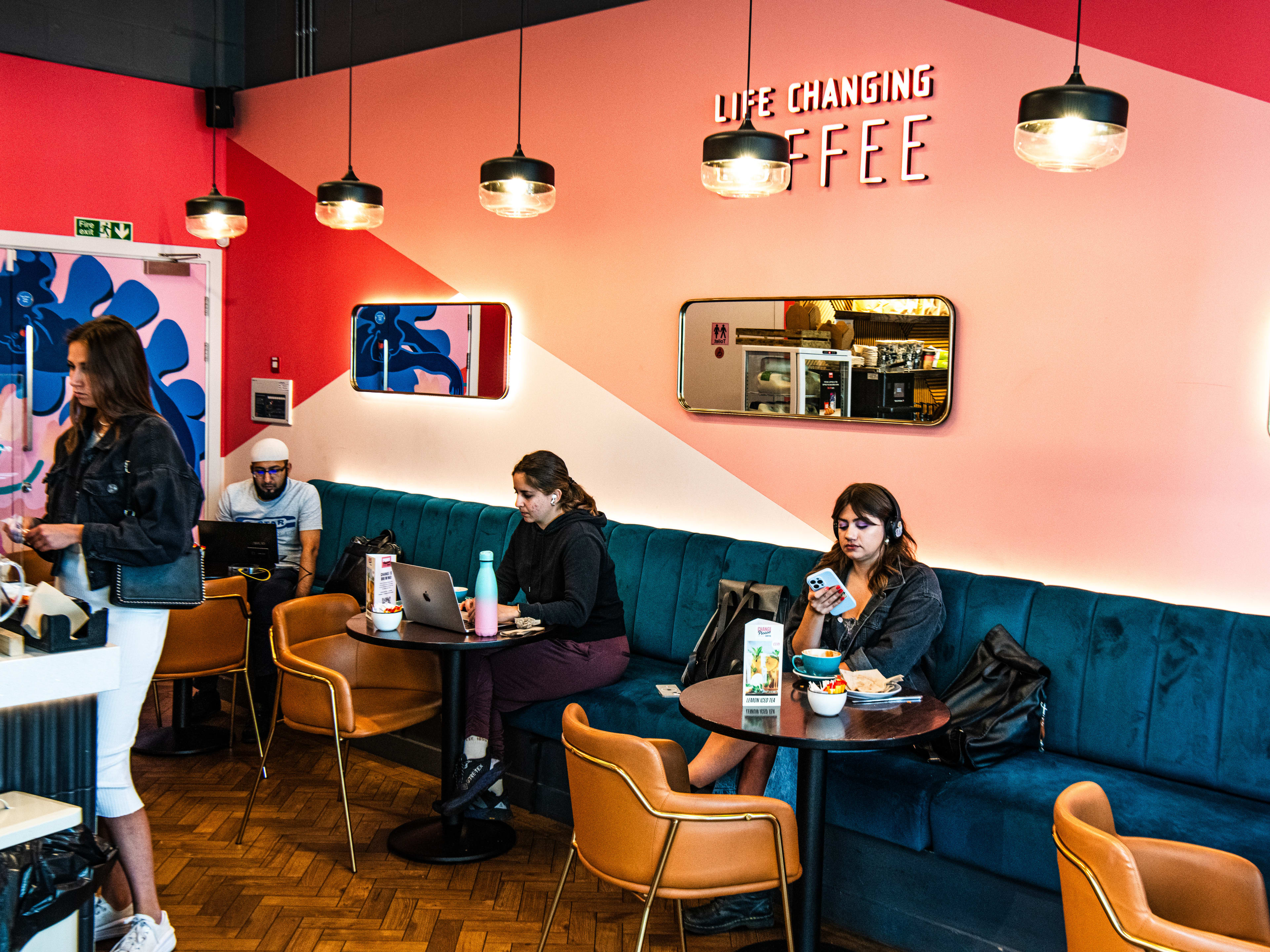 People sitting at tables at a blue velvet booth at Change Please.