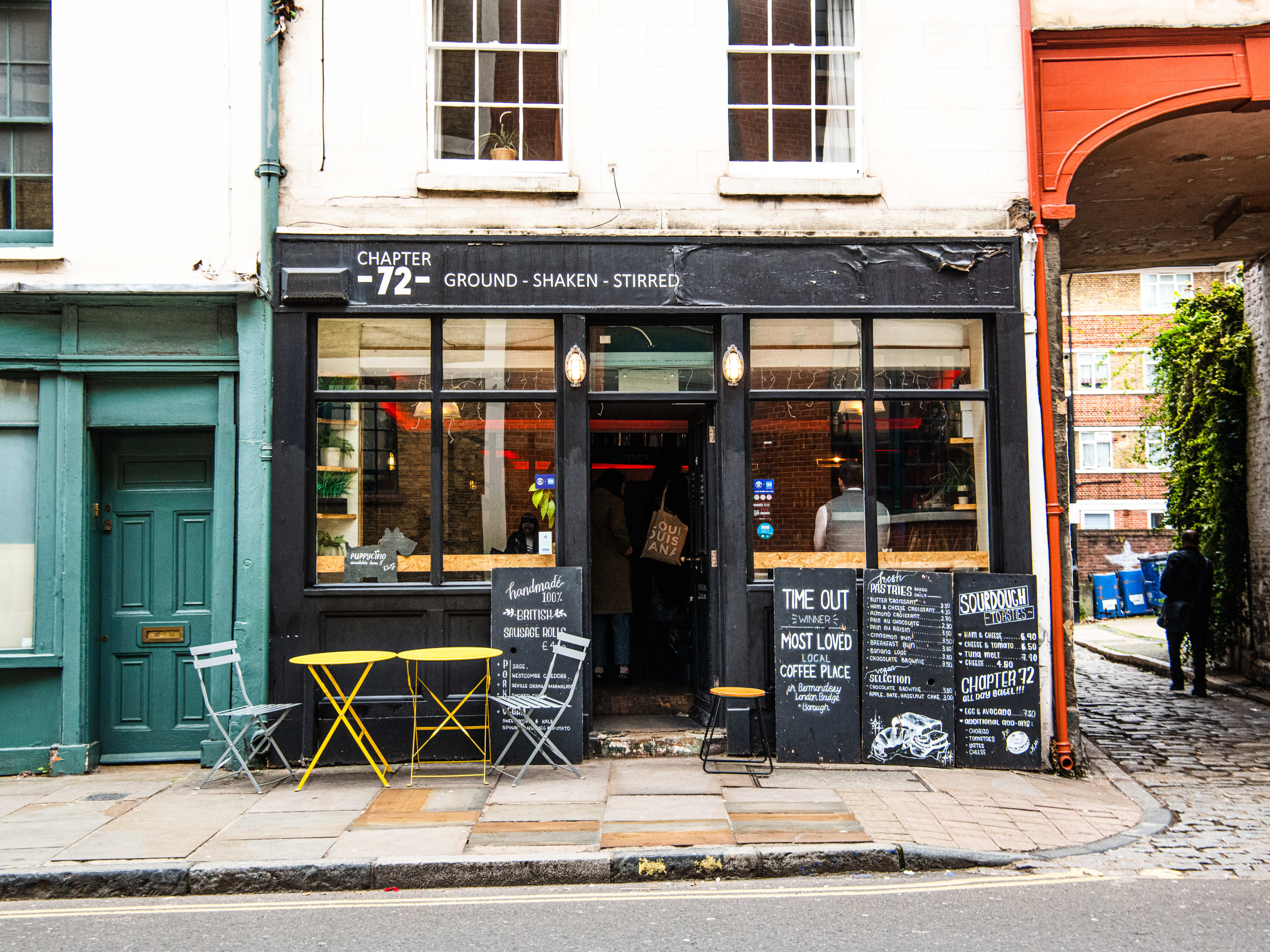 The exterior of Chapter 72 on a cobblestone corner. There are small tables available to sit at outside.