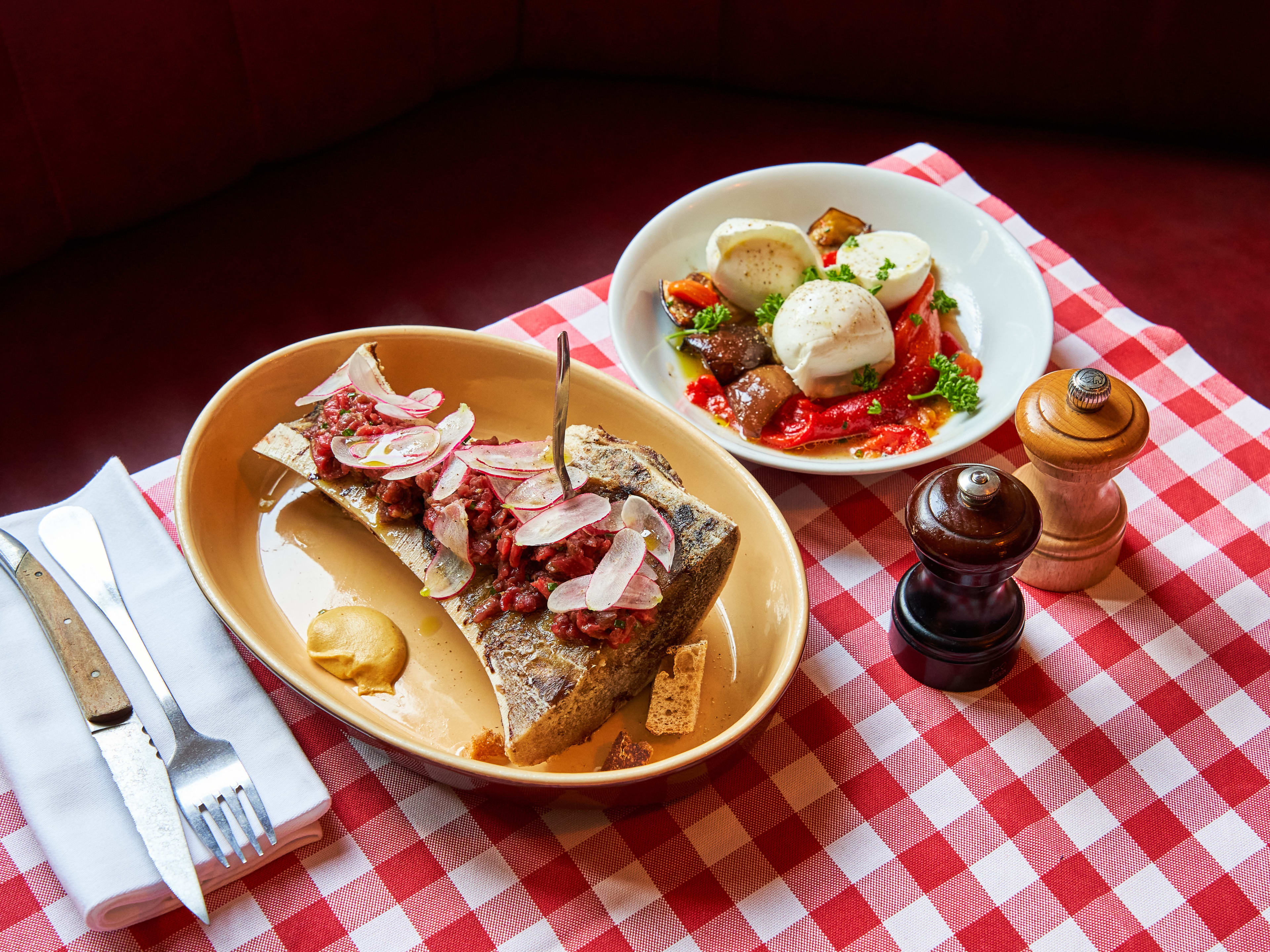 Bone marrow dish with side of mozzarella salad on red checkered tablecloth at Chez Marius