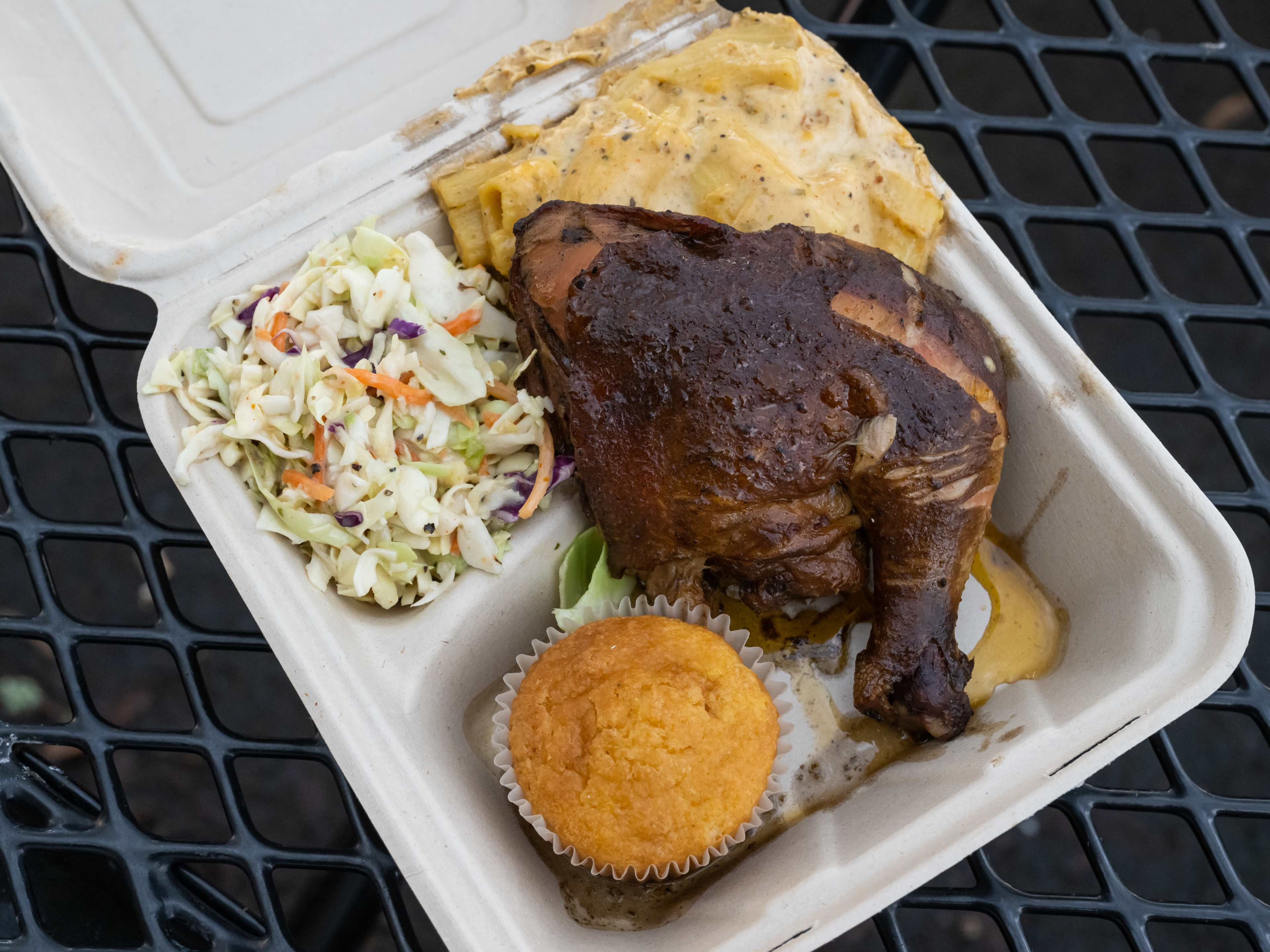 jerk chicken meal in takeout box with slaw and corn muffin