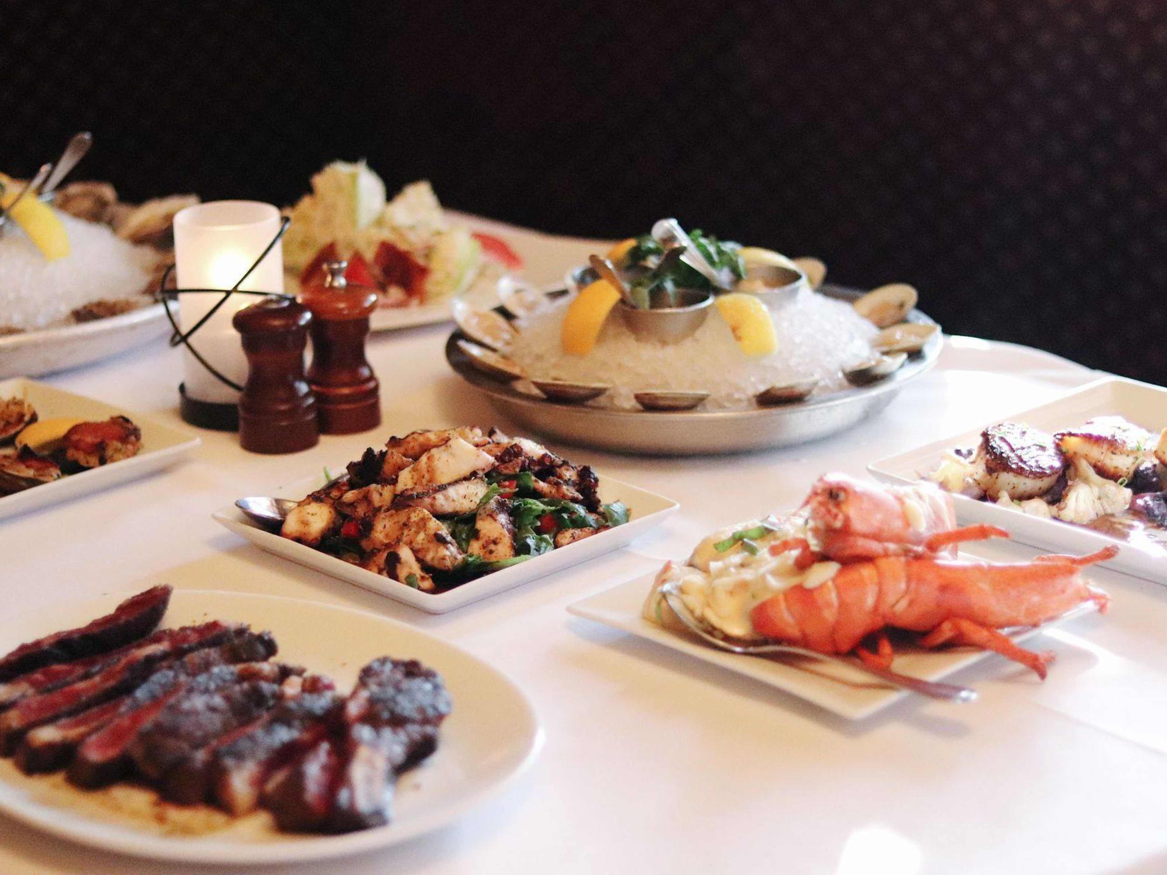 Lobster, oysters, steak, and other dishes on a table.